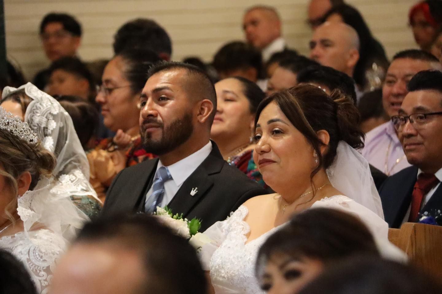 Guests seated attentively at a formal indoor event, wearing suits and dresses