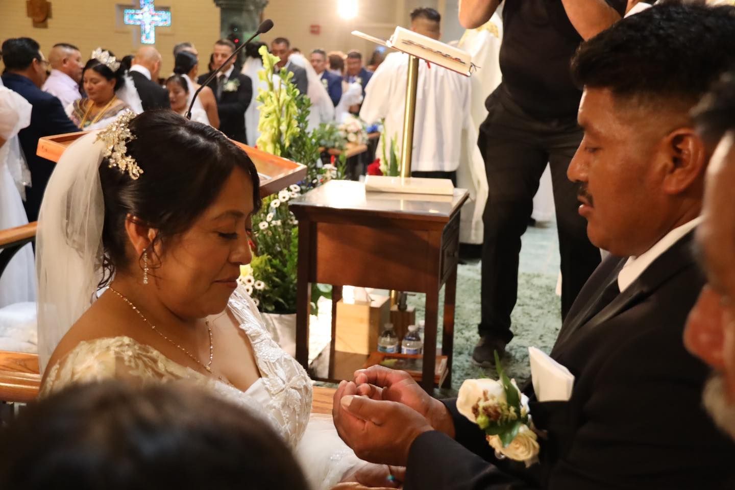 Bride and groom holding hands during a church wedding ceremony, with officiant at the altar