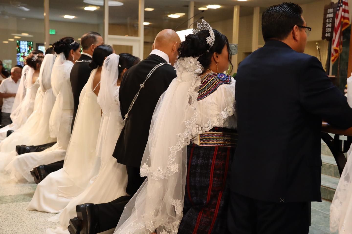 People in formal attire standing in a line at a wedding ceremony indoors