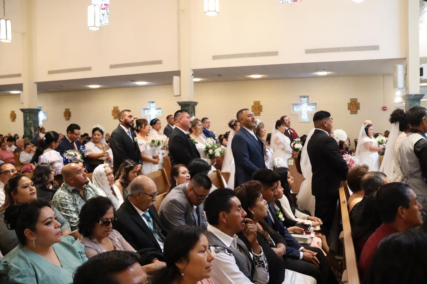 People seated and standing in a church or hall, facing forward during a formal gathering.