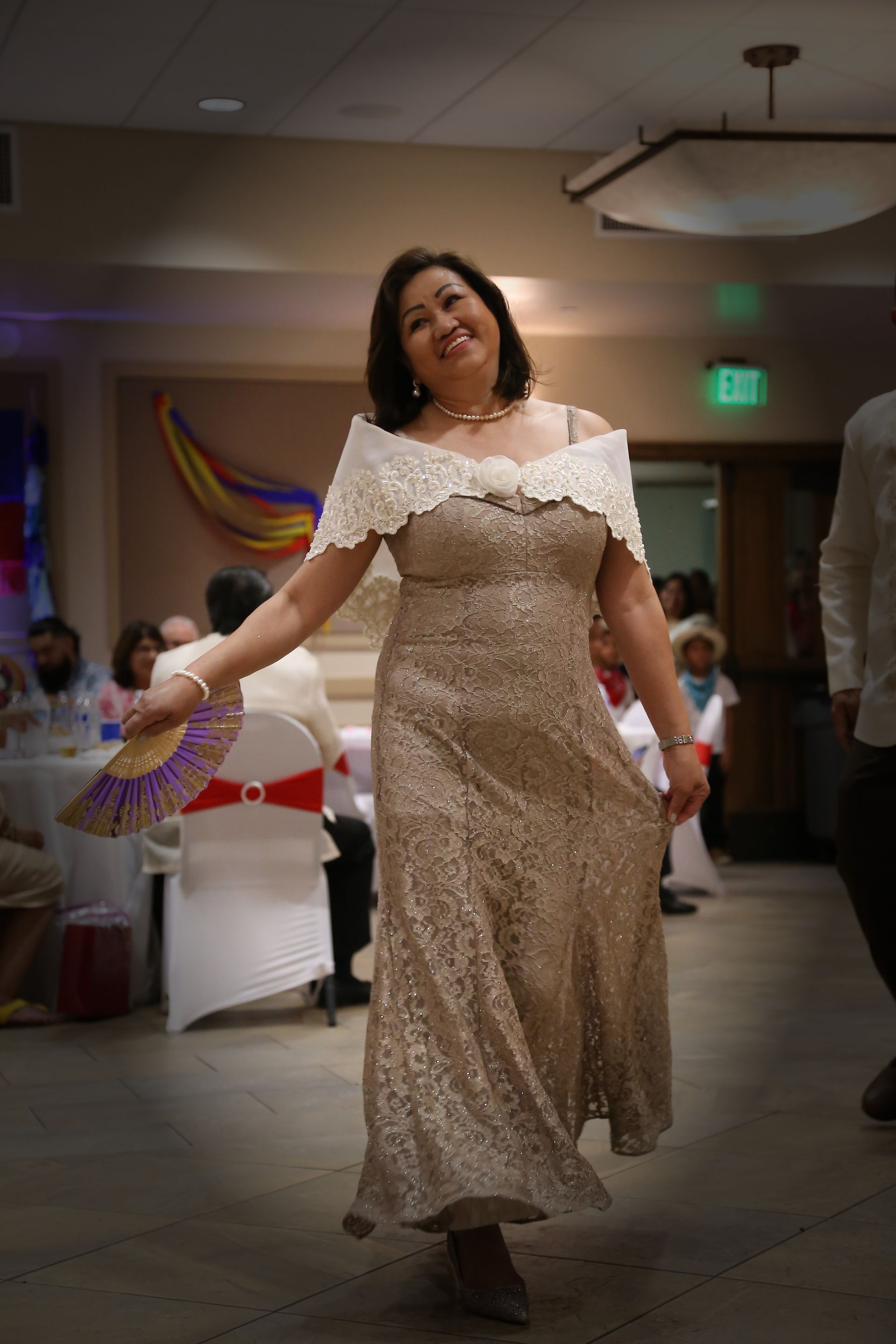 Woman in a sparkling off-shoulder dress walking through a decorated indoor event hall