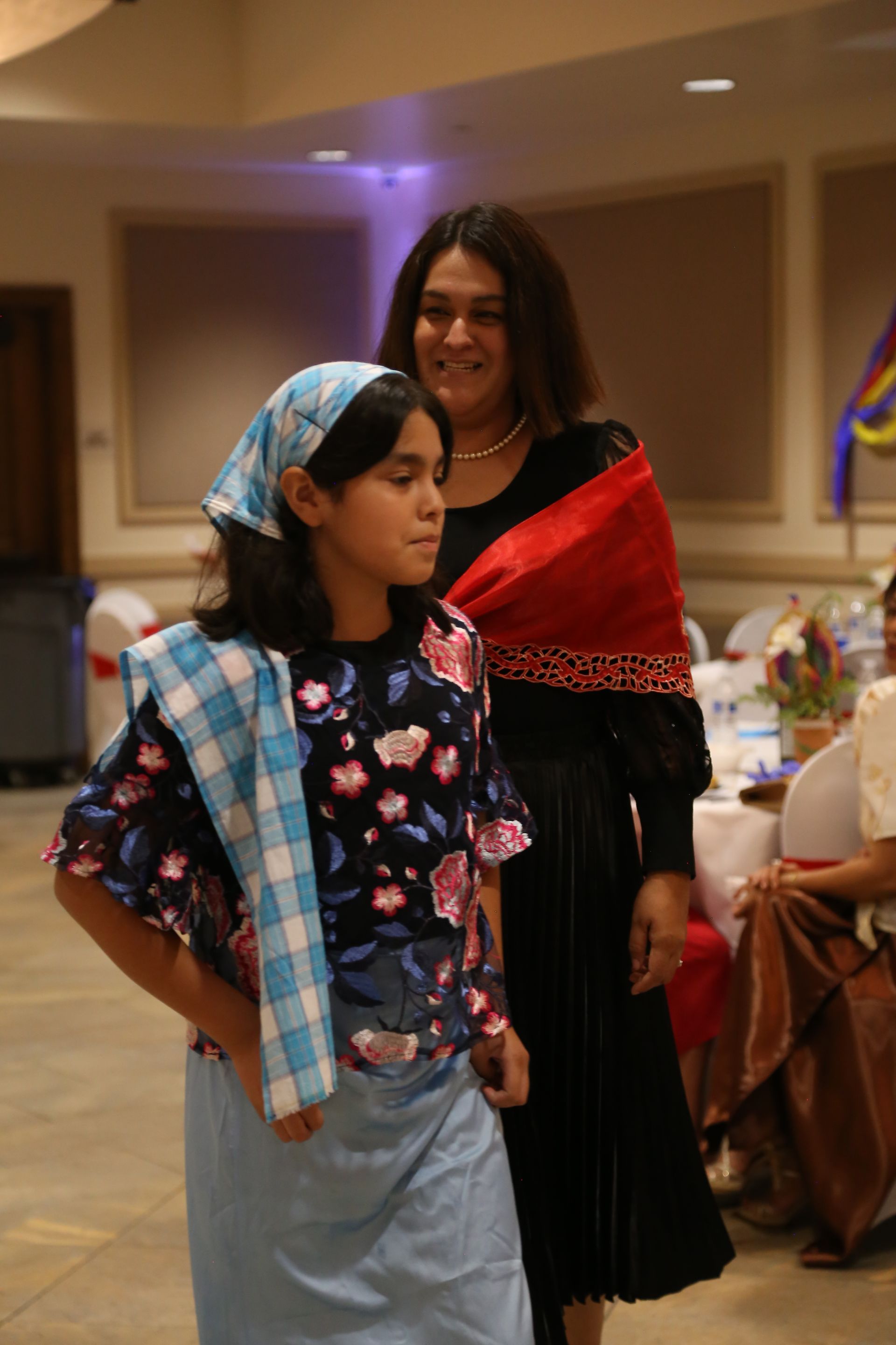 Two people in colorful traditional clothing standing indoors at a formal event