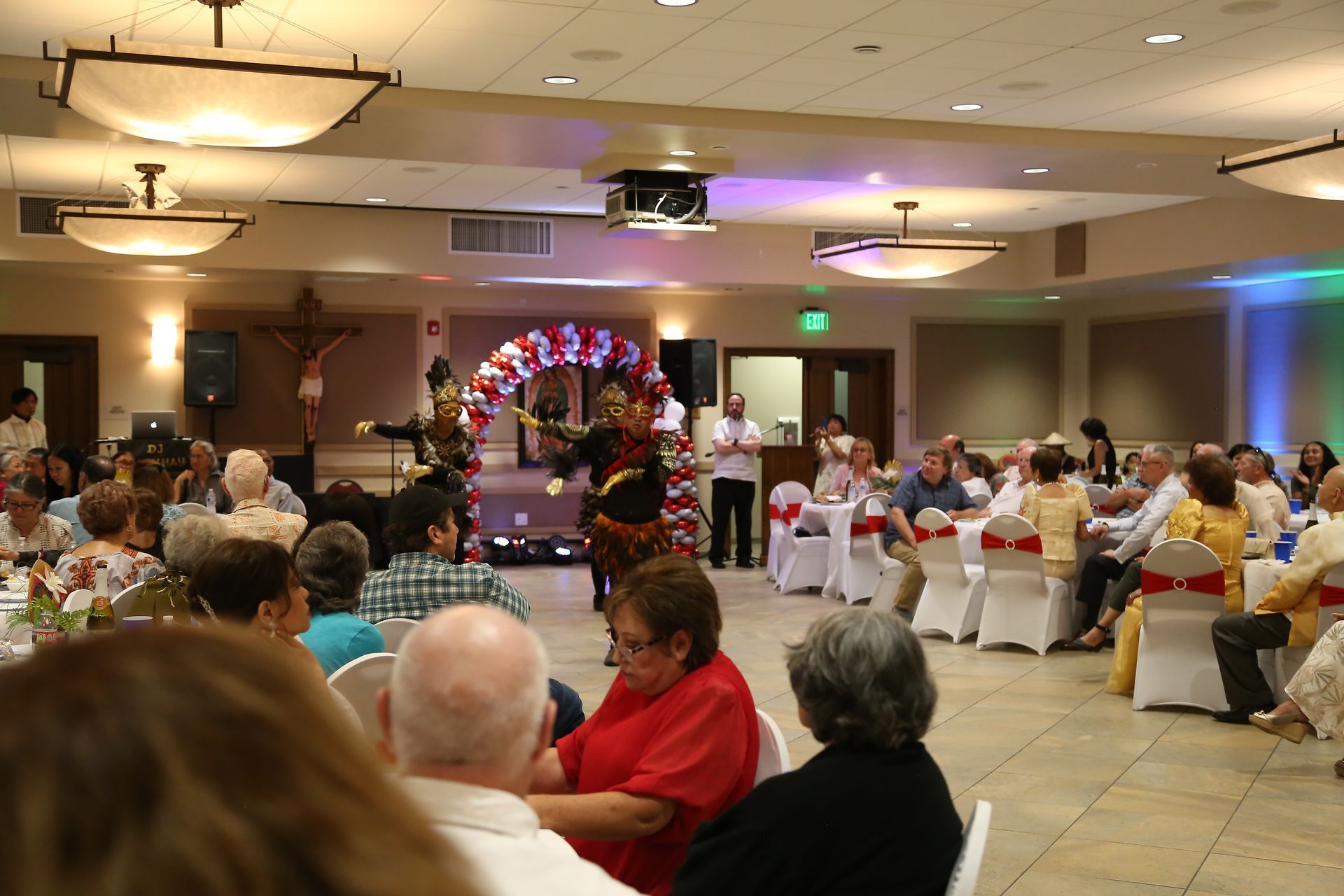 Banquet hall with seated guests watching a decorated stage and lit archway