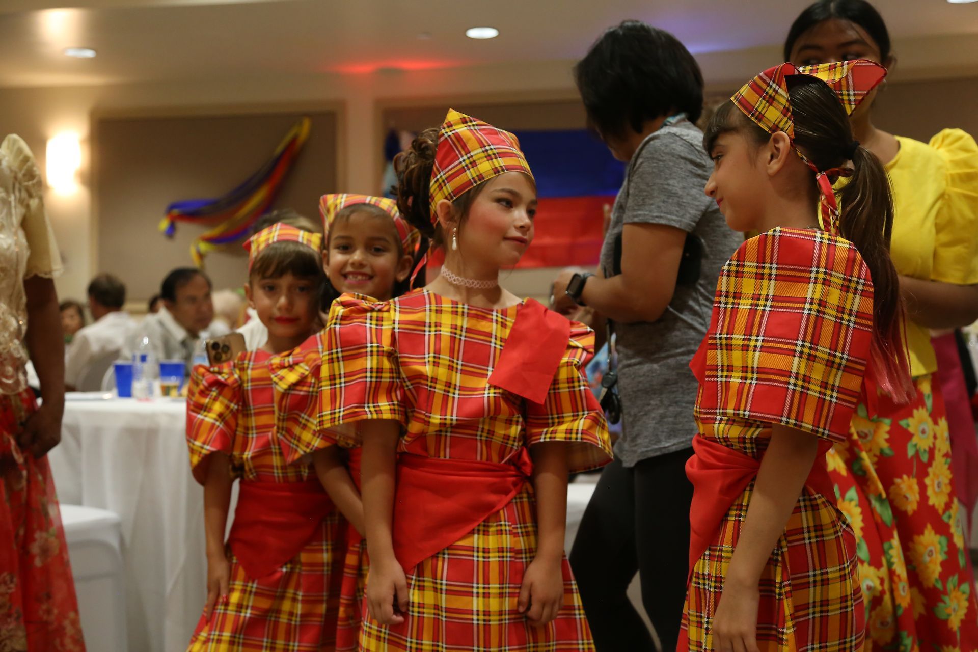 Group of children in red and yellow traditional outfits at a festive indoor event