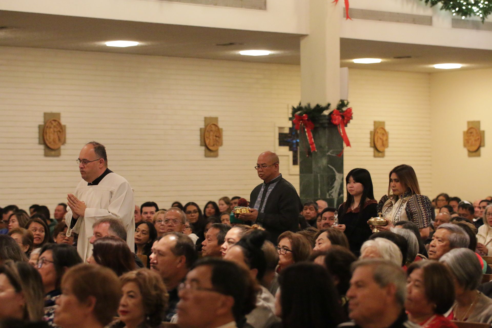 Audience seated in a hall with two people standing near a decorated column during an event