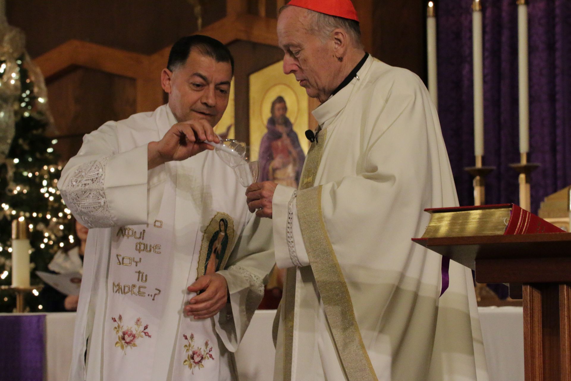 Priest adjusting the robe of a pope in white vestments during a church ceremony