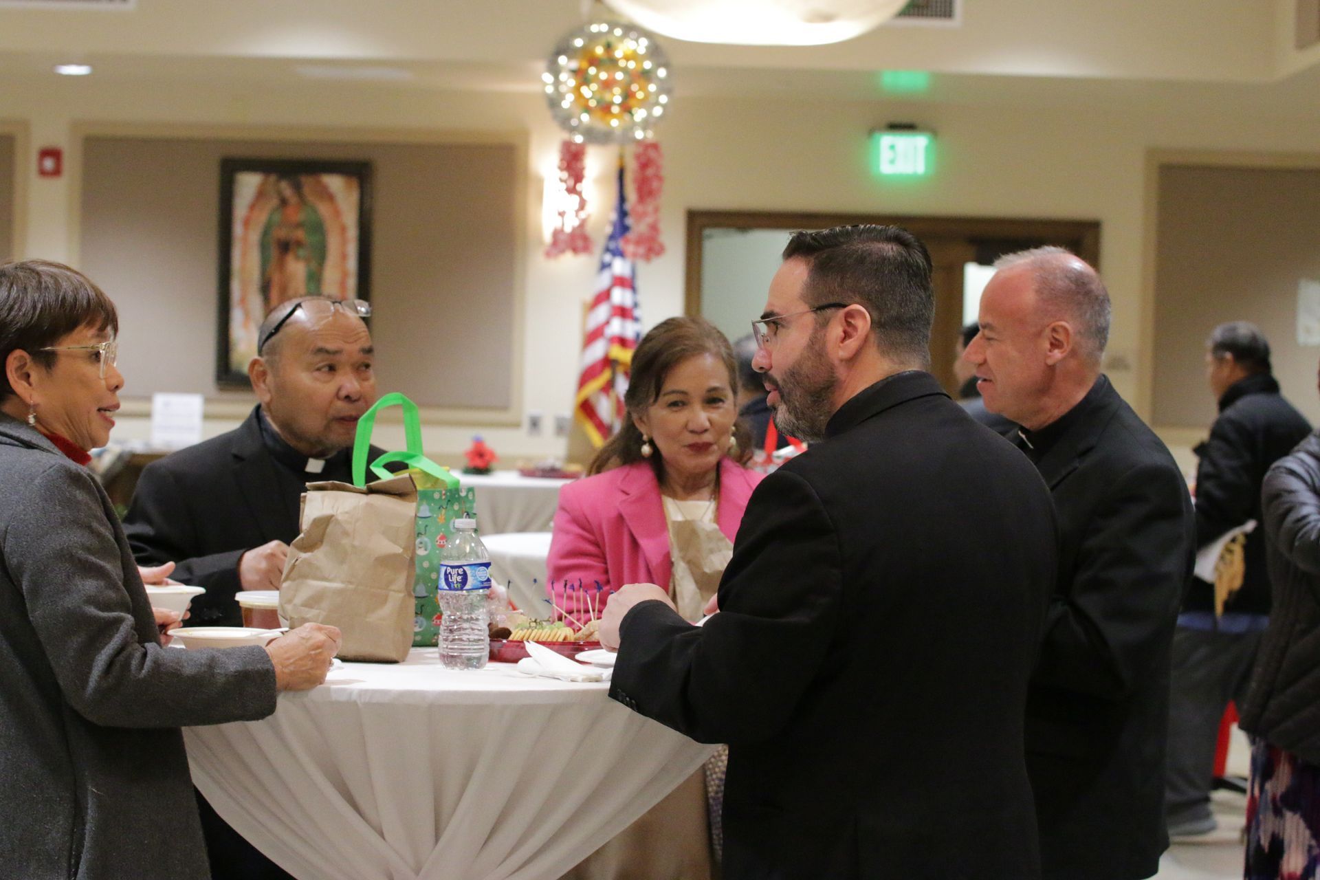 People seated at a round table chatting during an indoor social gathering with drinks and snacks