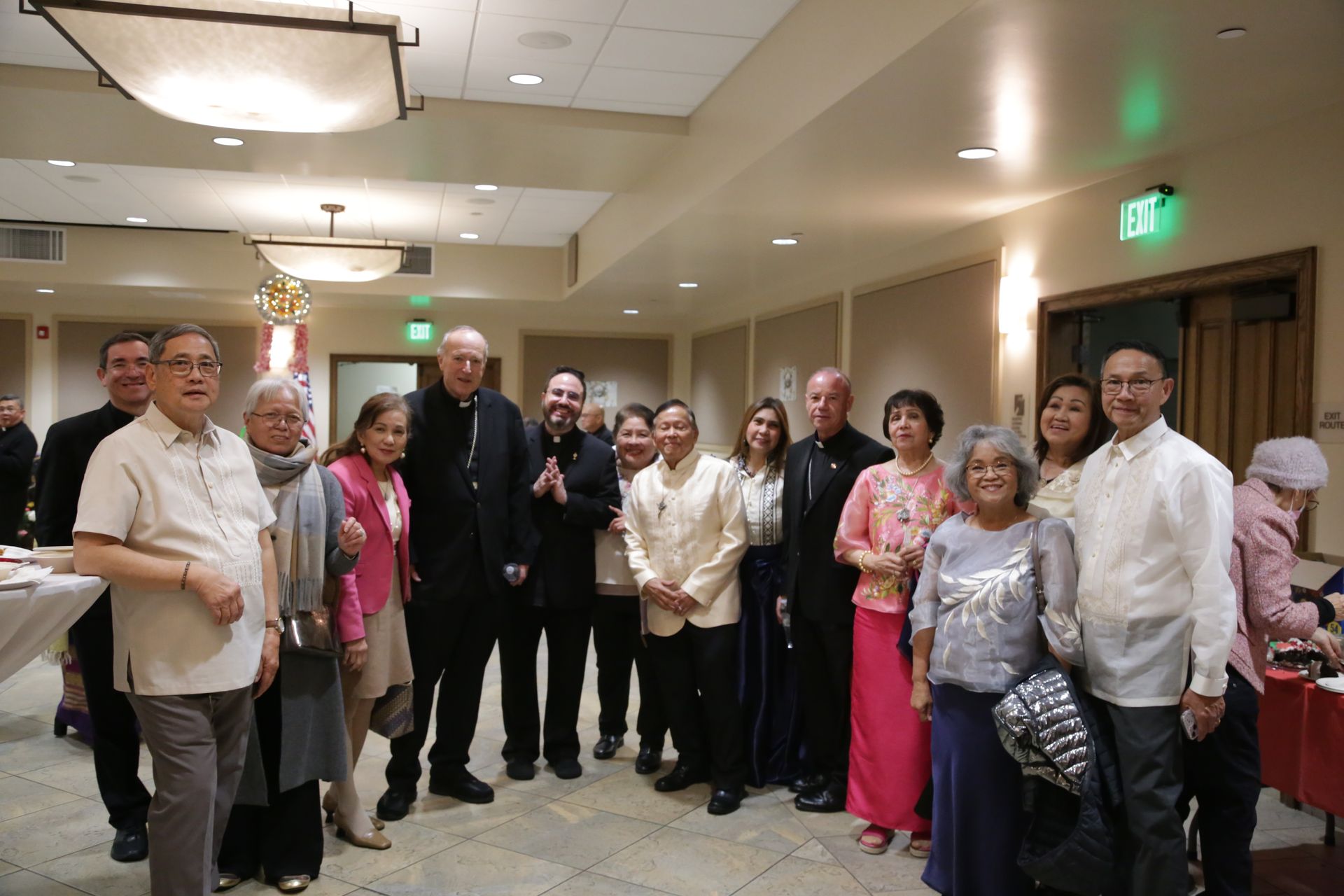 Group of people posing indoors at a formal event, with one man holding a microphone.