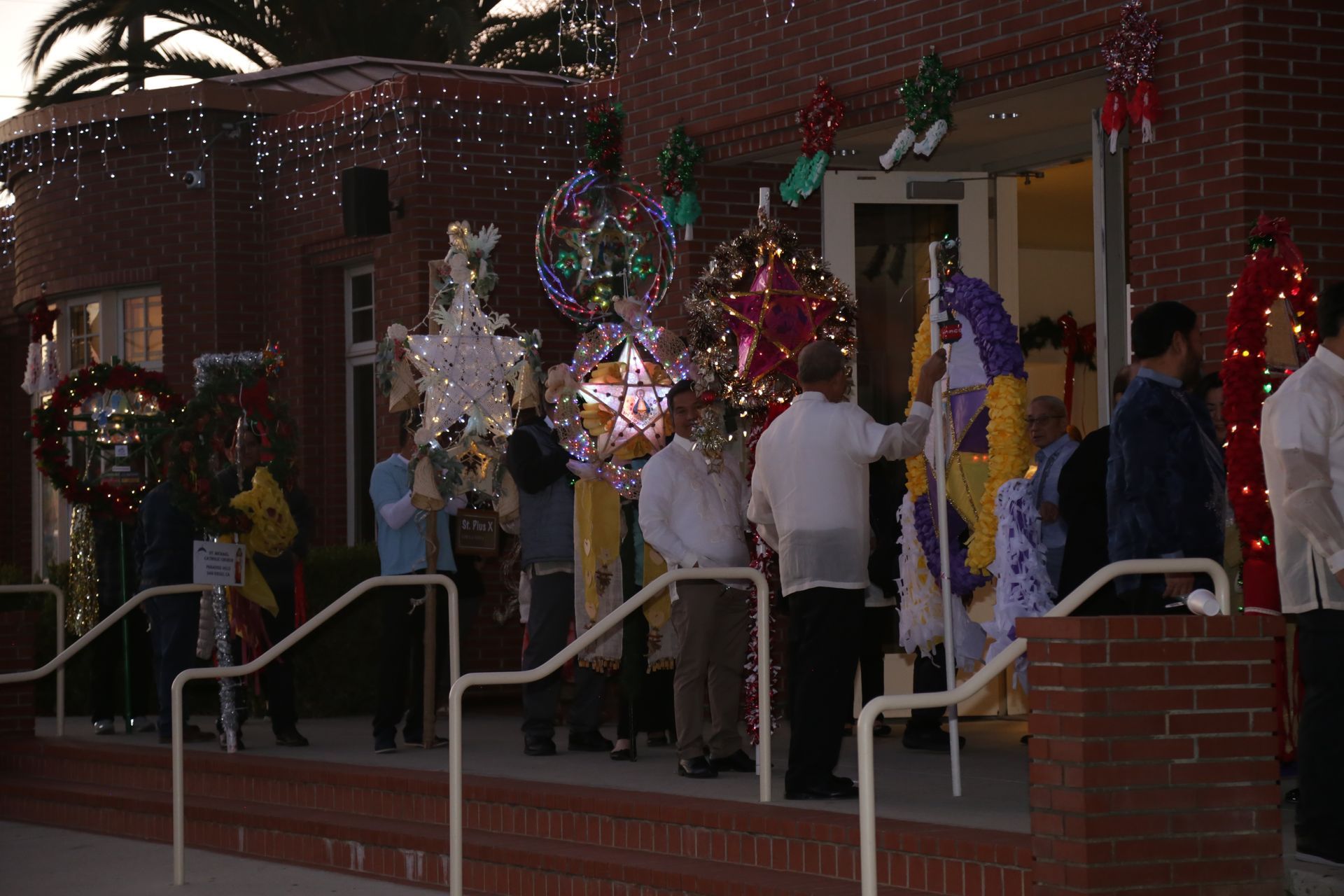 People gathered on a porch at night with colorful balloon decorations and holiday lights.