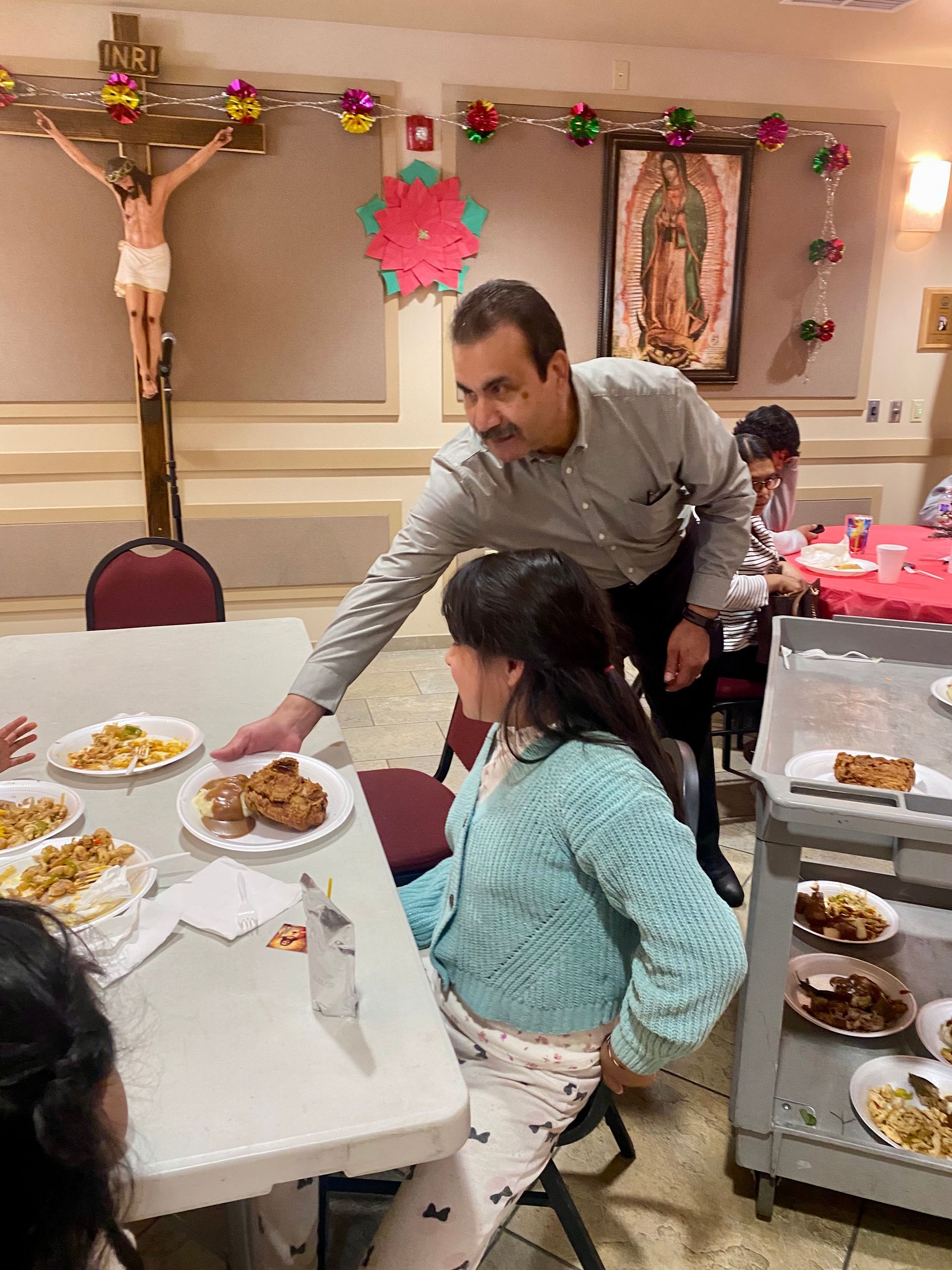 Person serving food to a seated child at a decorated indoor dining table with plates of snacks