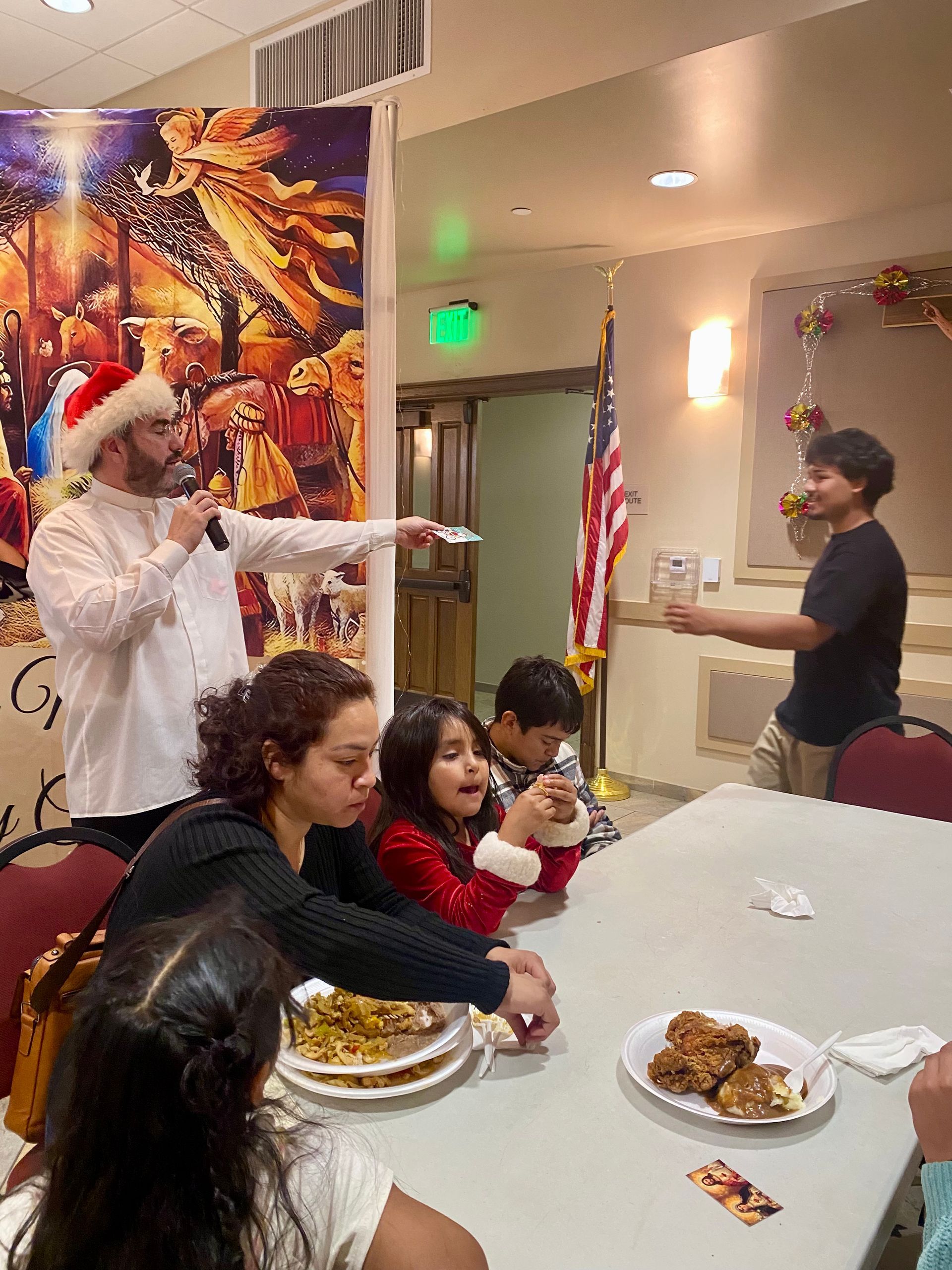 Santa Claus points at a person beside a decorated table at a festive indoor party