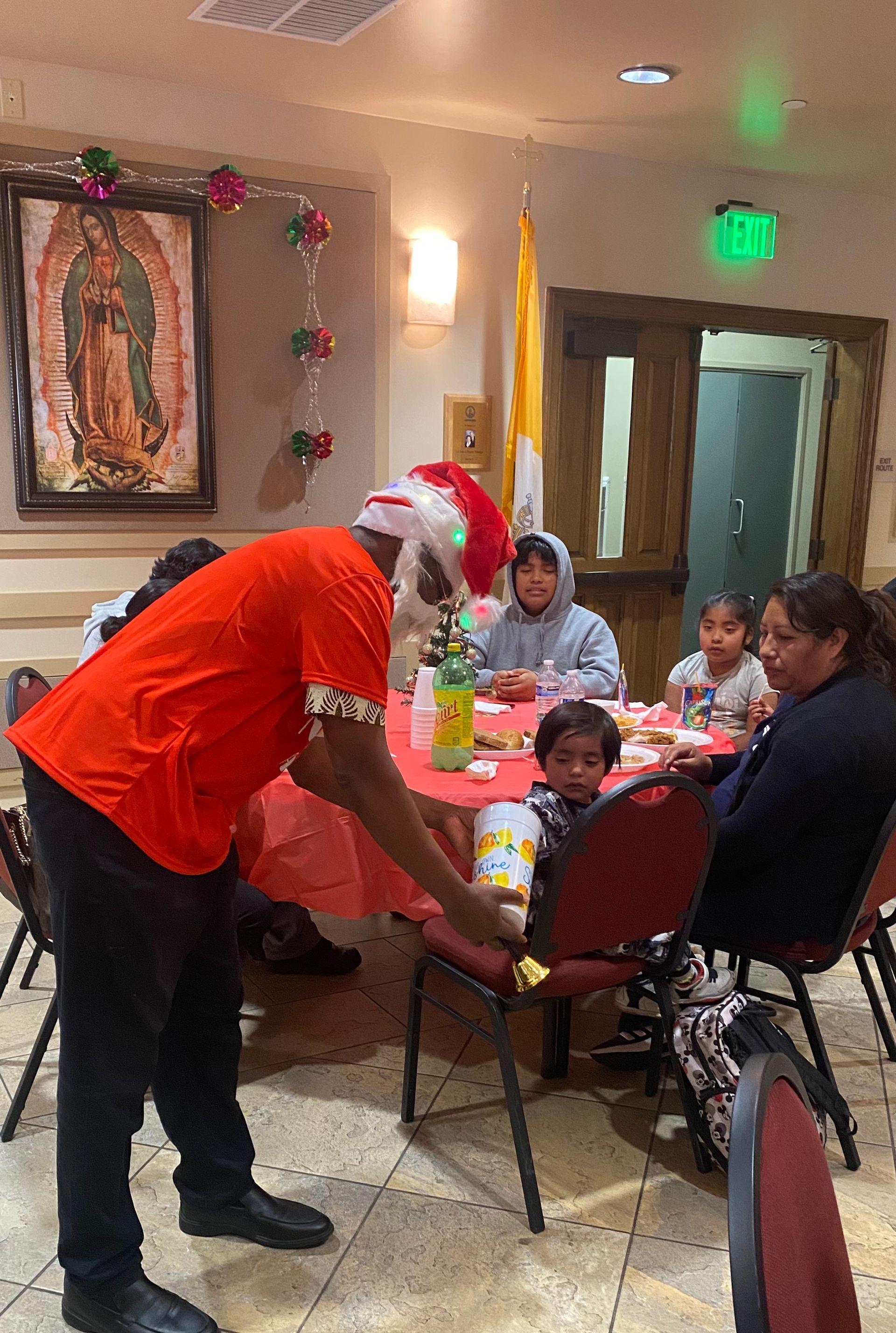 Santa leaning over a dining table with children and adults at a holiday gathering