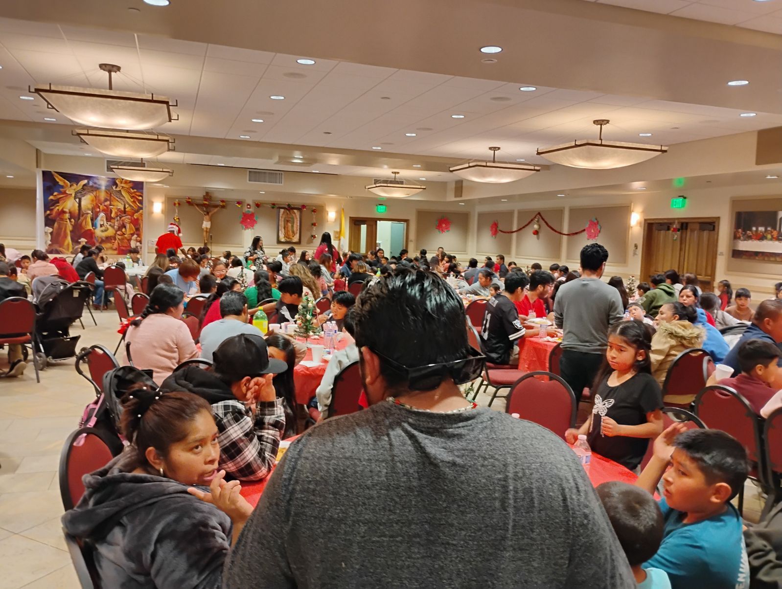 Crowded banquet hall with many seated guests and a decorated stage in the background