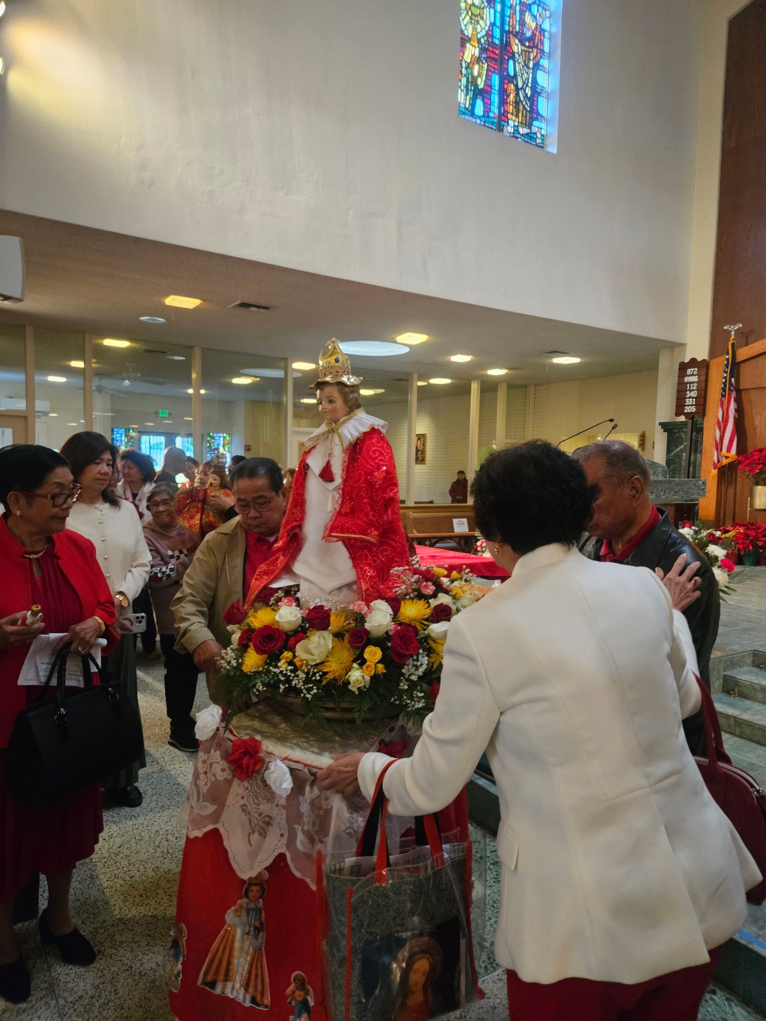 Ceremonial statue adorned with flowers being carried through a church aisle during a procession