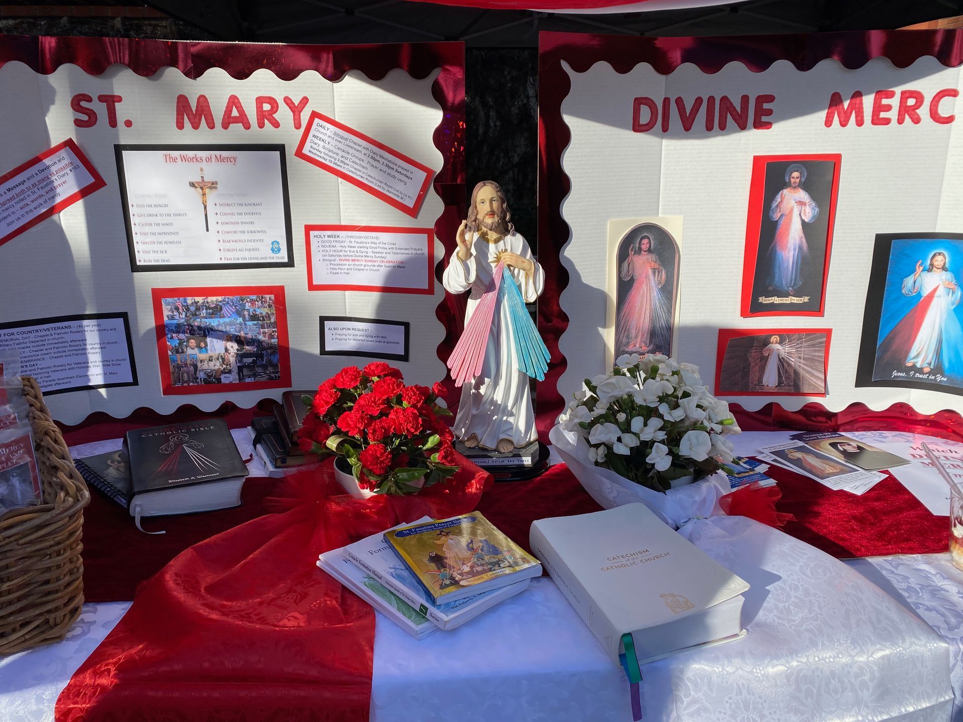 St. Mary and Divine Mercy altar display with religious posters, flowers, candles, and a statue of Mary