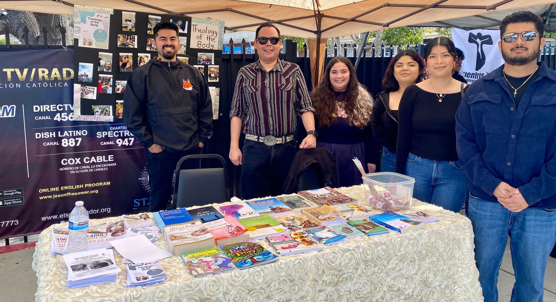 Five people standing behind a table of colorful packaged items at a market booth