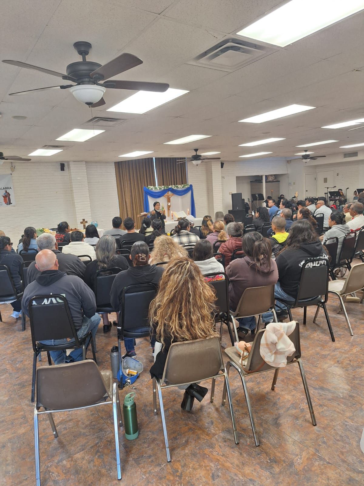 Audience seated in a community hall facing a decorated stage during a presentation