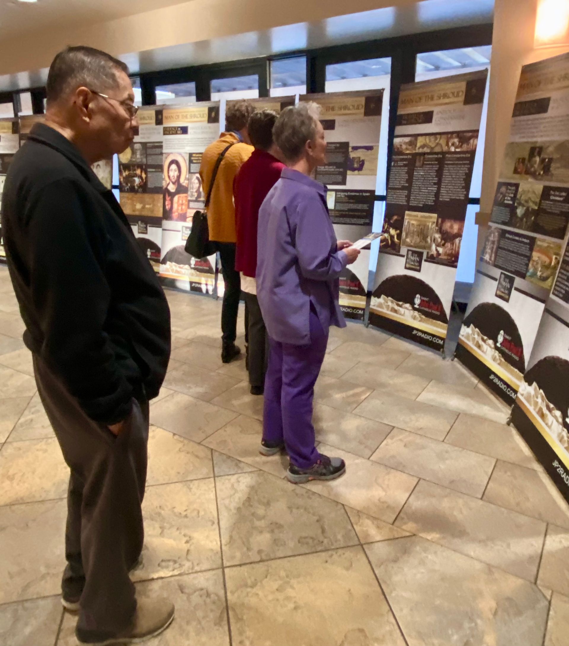People viewing display panels in a museum-like exhibit hall