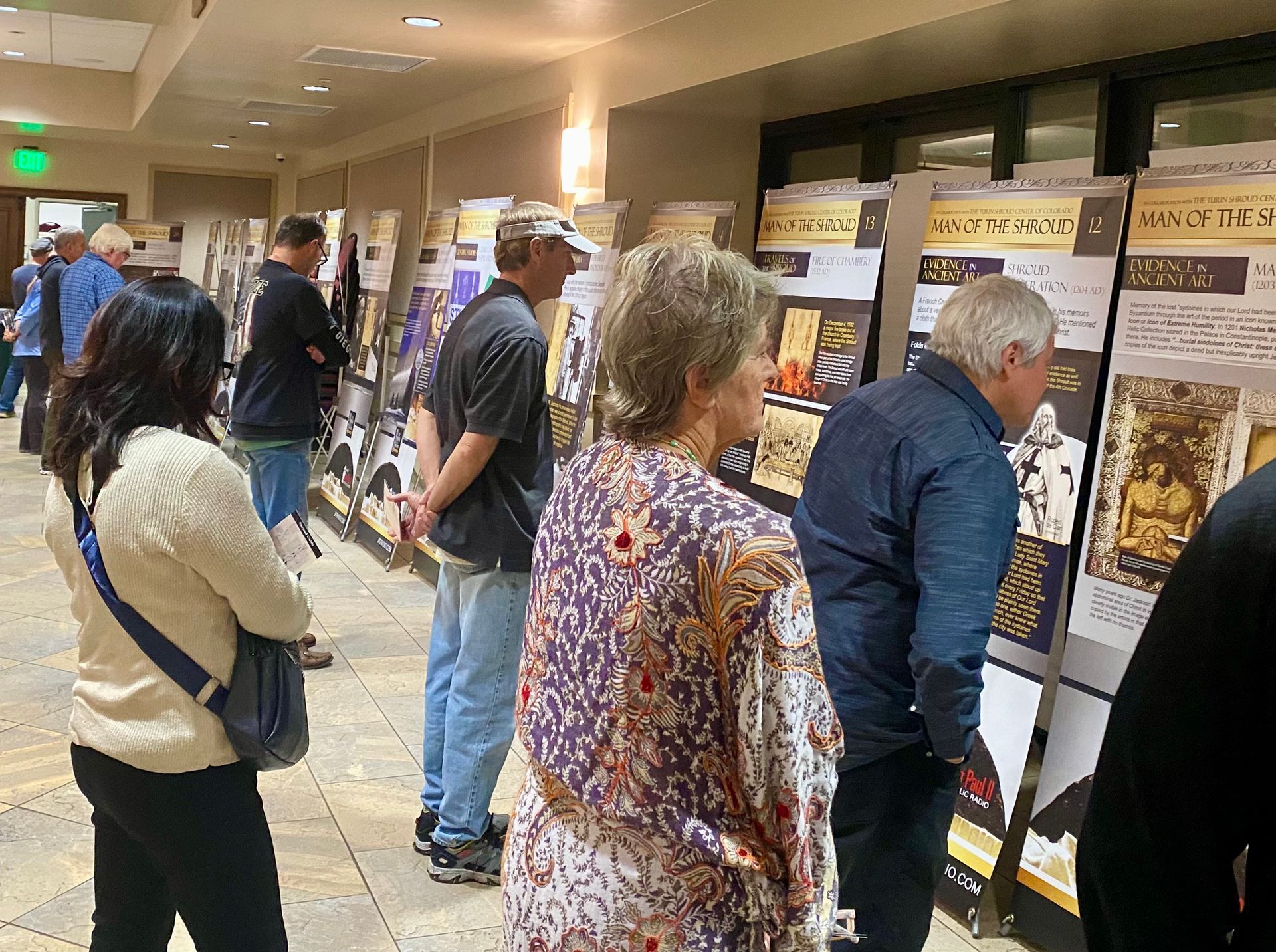 People viewing posters on display boards in a hotel hallway