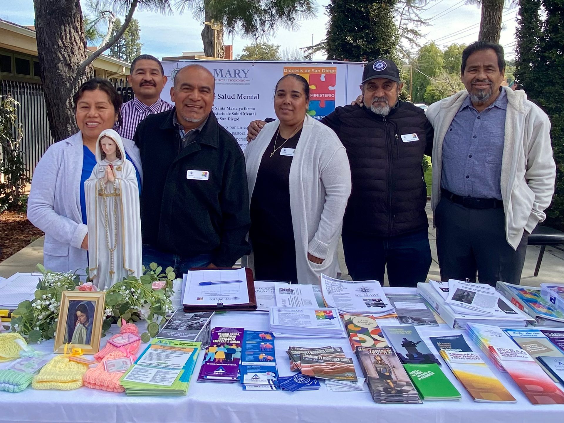 Group standing behind a table of books and devotional items at an outdoor community event