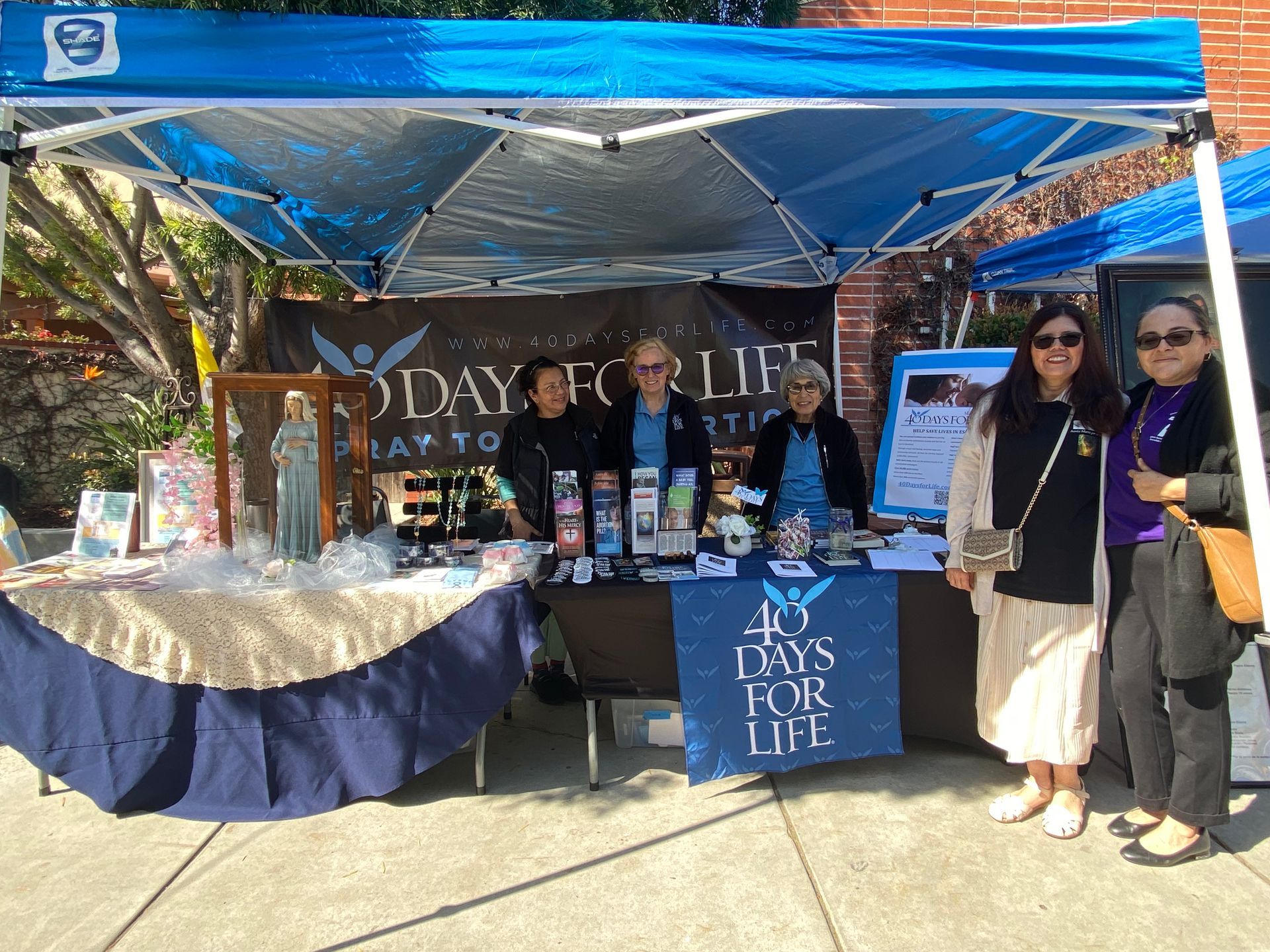 Booth under blue canopy with people behind a Days for Life table display and flyers