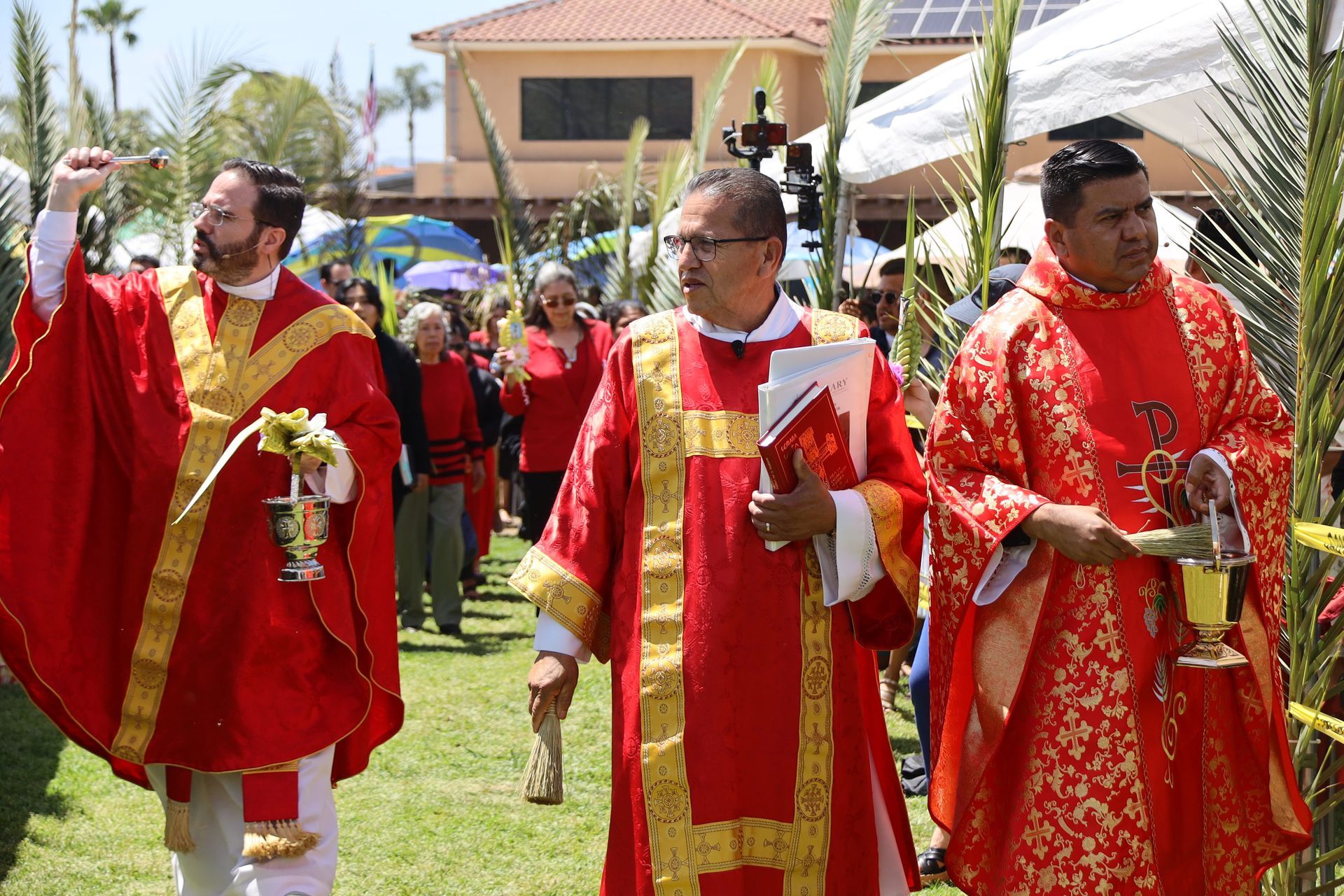 People in red and gold ceremonial robes walking outdoors at a religious procession