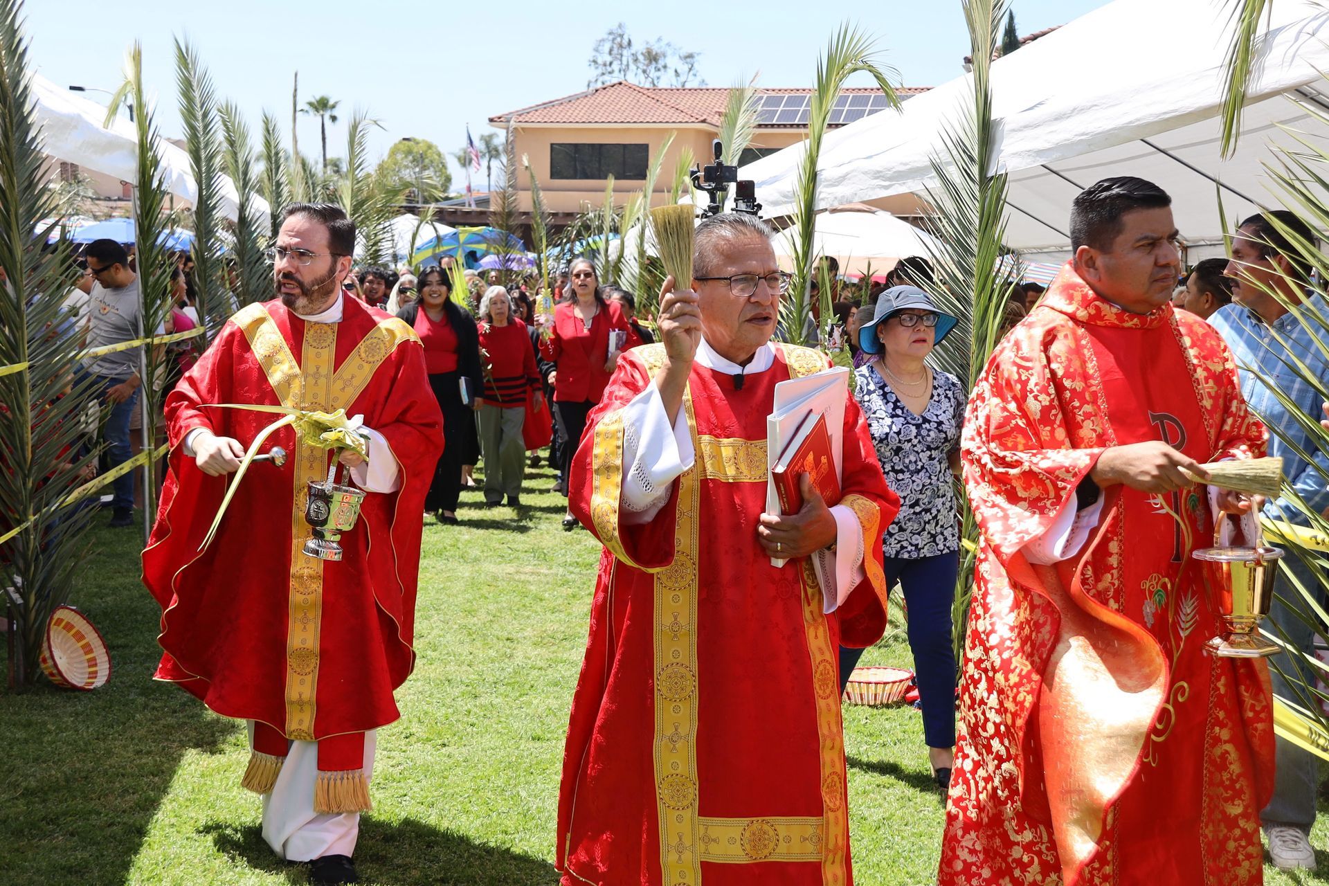 People in red and gold ceremonial robes walking outdoors in a procession