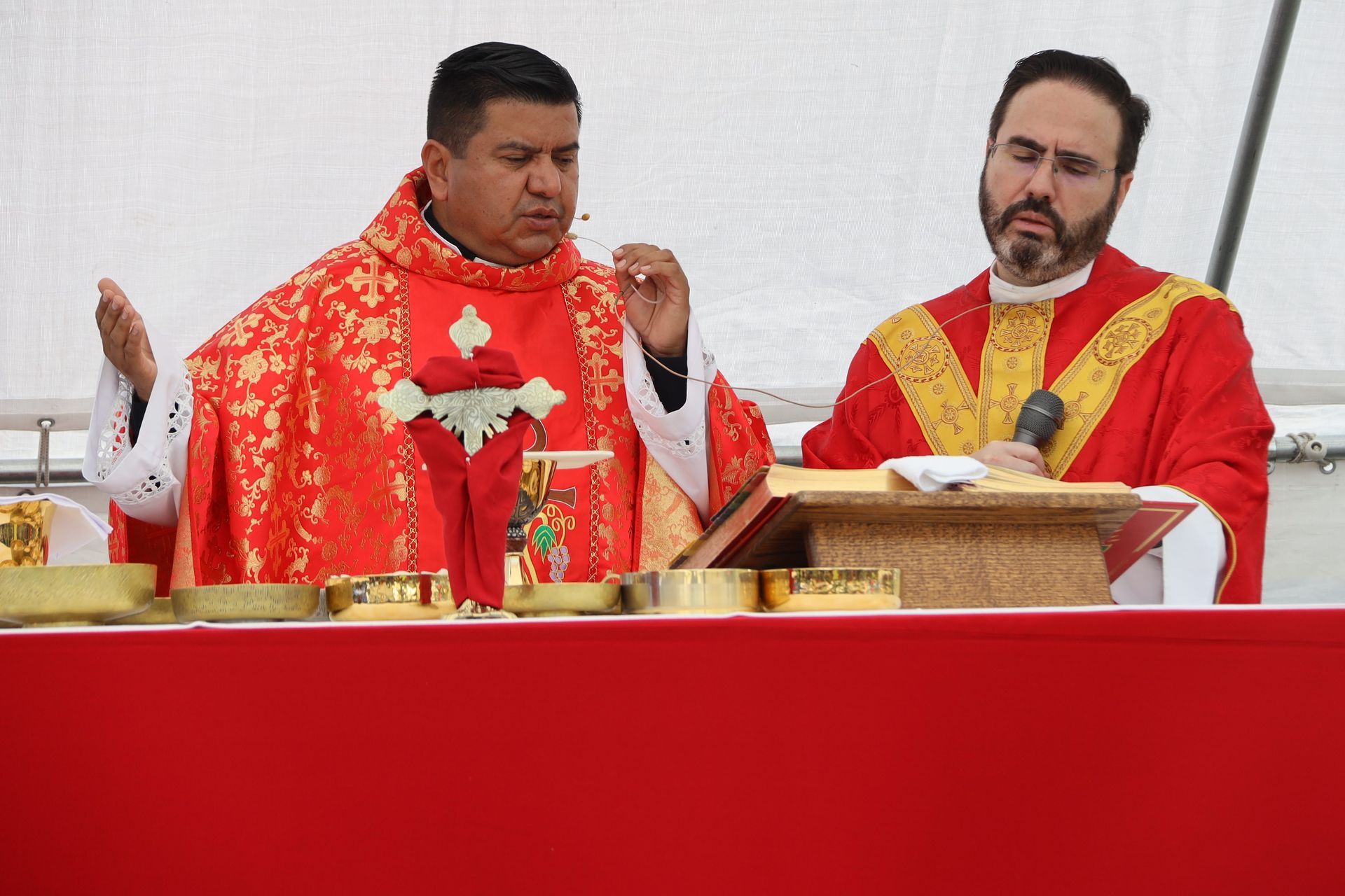 Two priests in red vestments at an altar during a church service