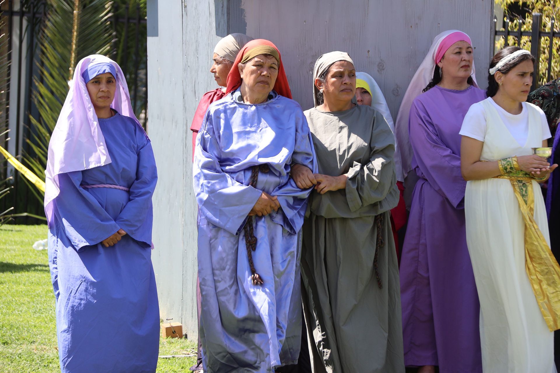 Five people in long robes and head coverings standing outdoors in sunlight