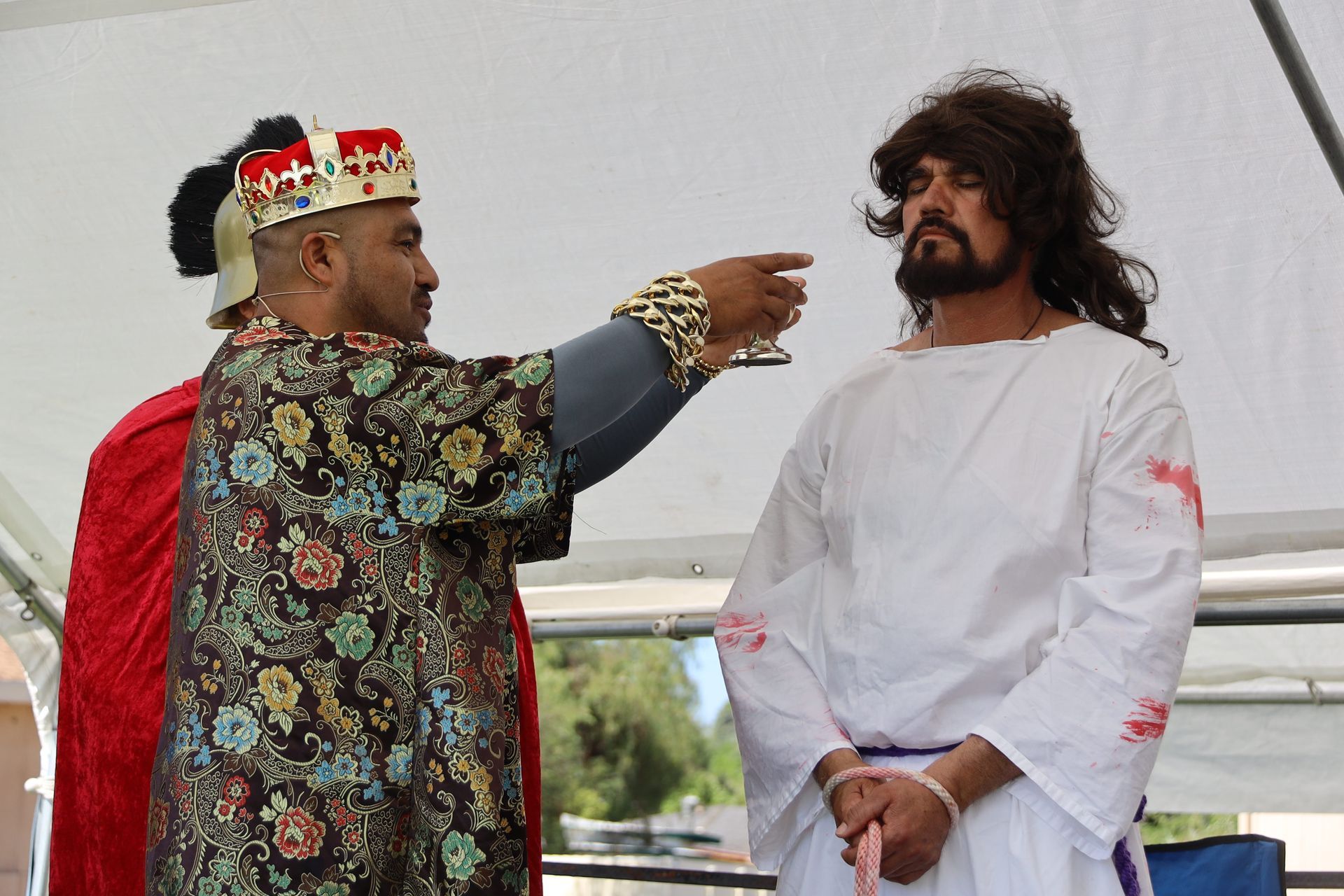 Two people on a stage, one pointing toward the other during a ceremonial moment.