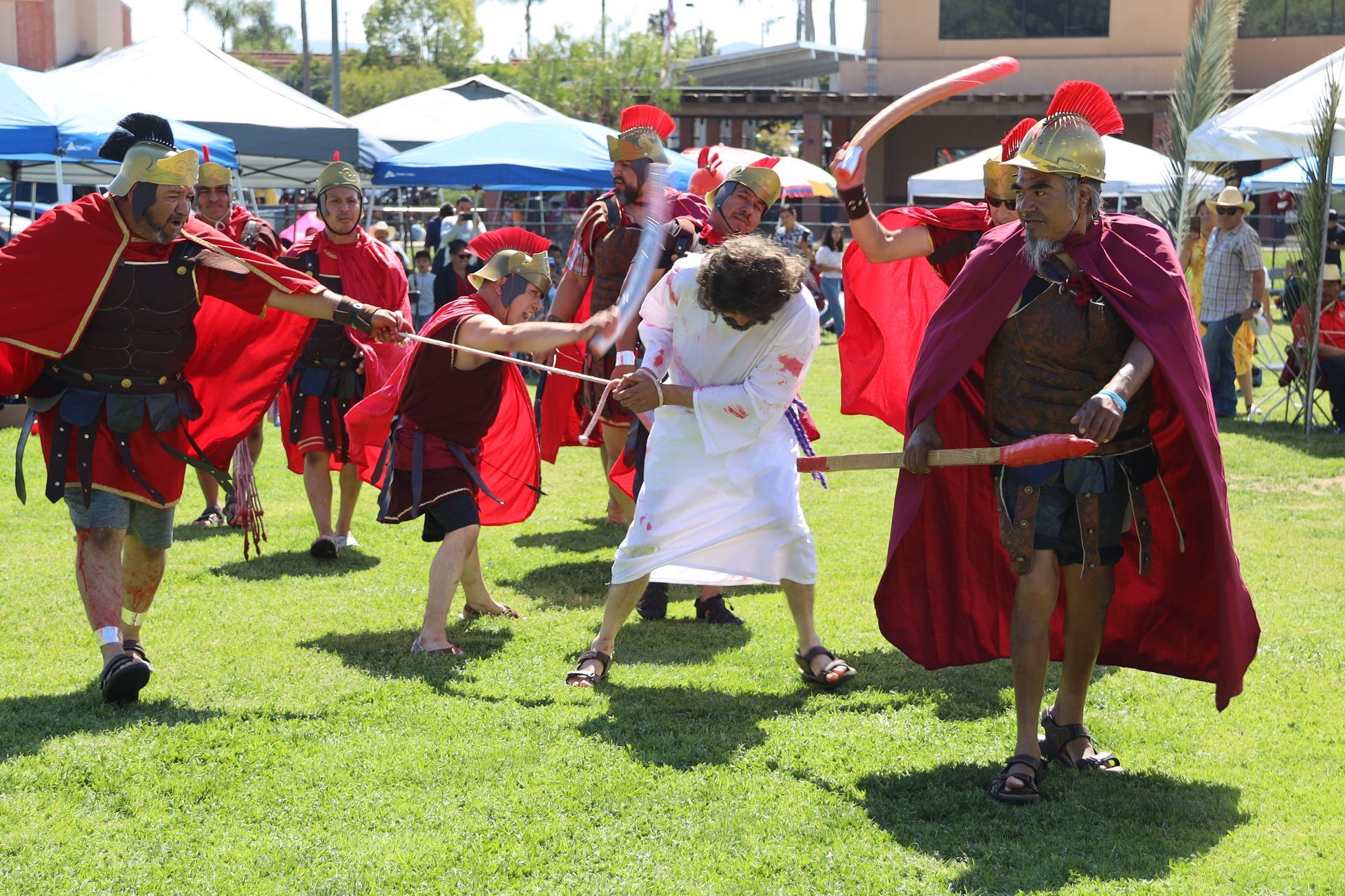 People in red and white costumes dancing outdoors on a grassy field at a festival