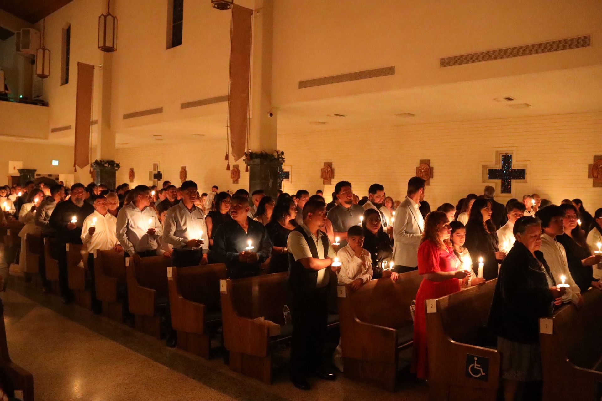 People holding candles in a dimly lit church during a candlelight service