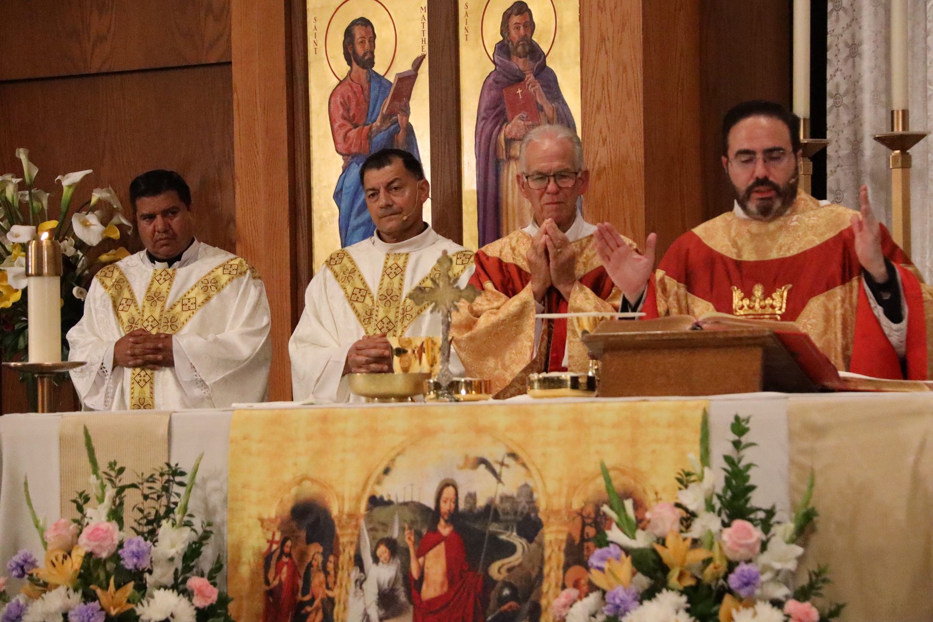 Priests celebrating Mass at an altar with gold vestments and religious icons in a church