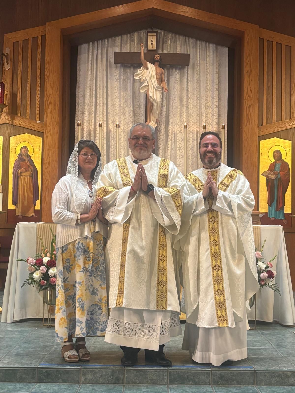Three clergy in white and gold vestments standing before an altar in a church chapel