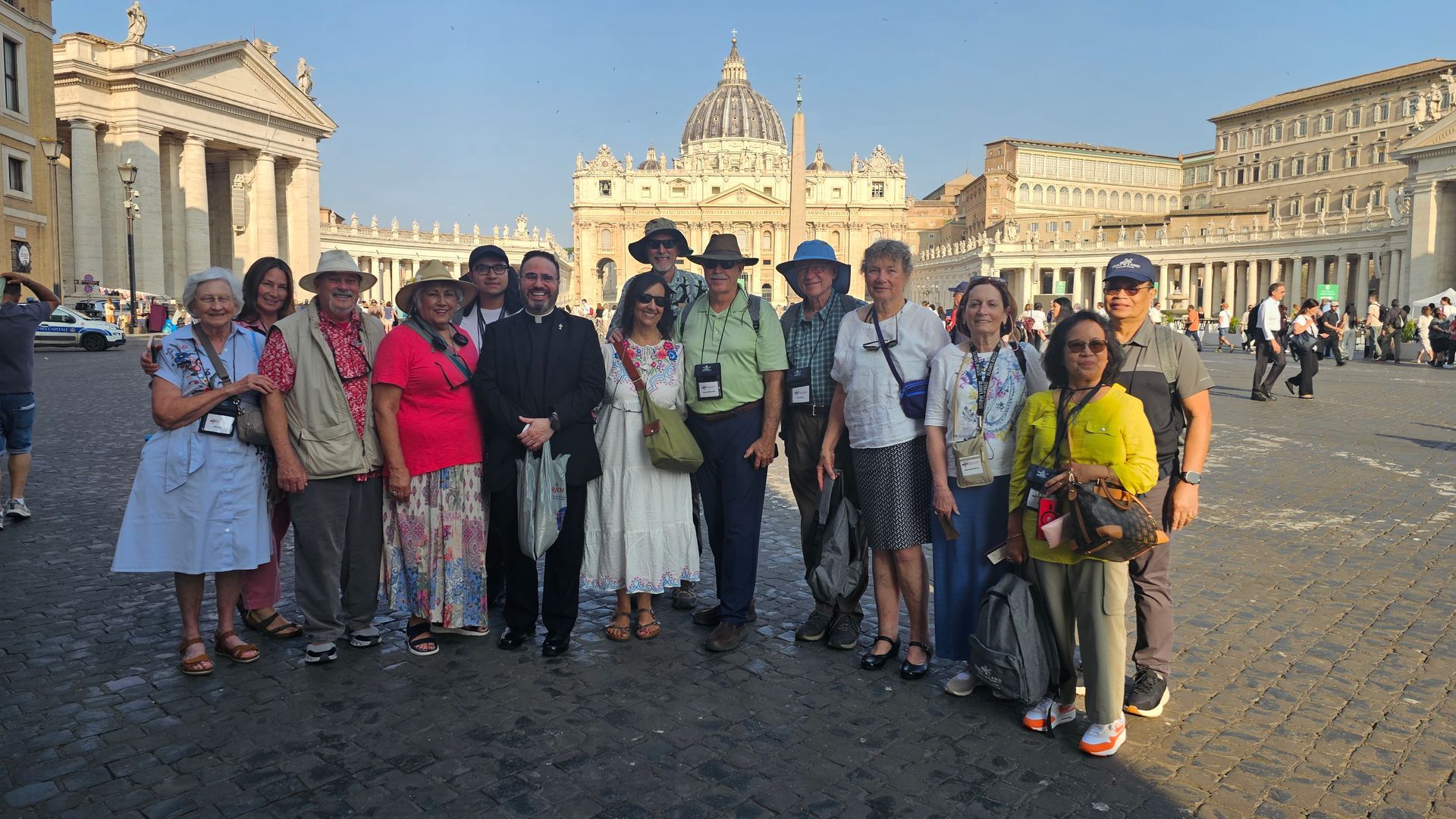 Group of people posing in St. Peter’s Square, with St. Peter’s Basilica in the background at sunset.