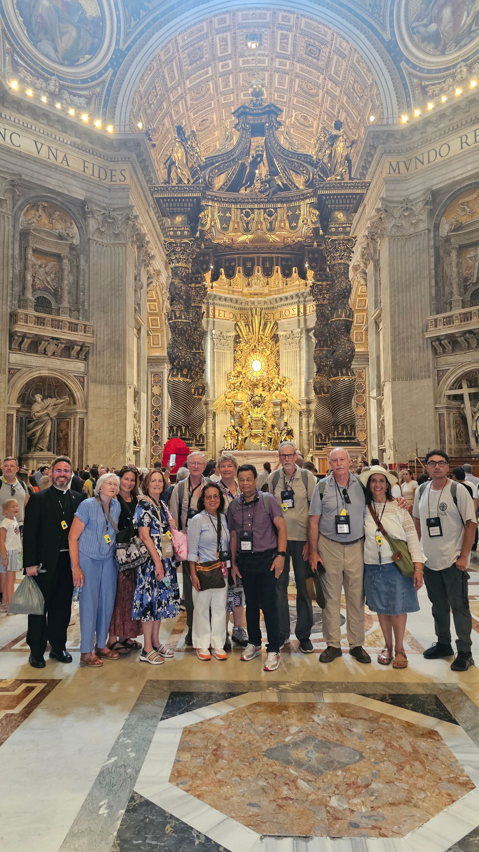 Group posing inside an ornate cathedral, with a gilded altar and elaborate ceiling artwork behind them.
