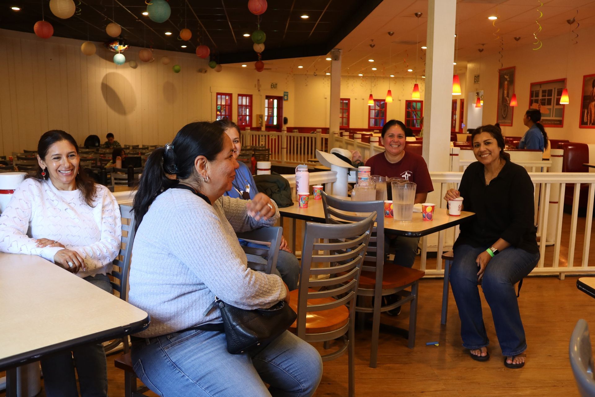 People sitting and chatting at tables inside a brightly lit casual restaurant