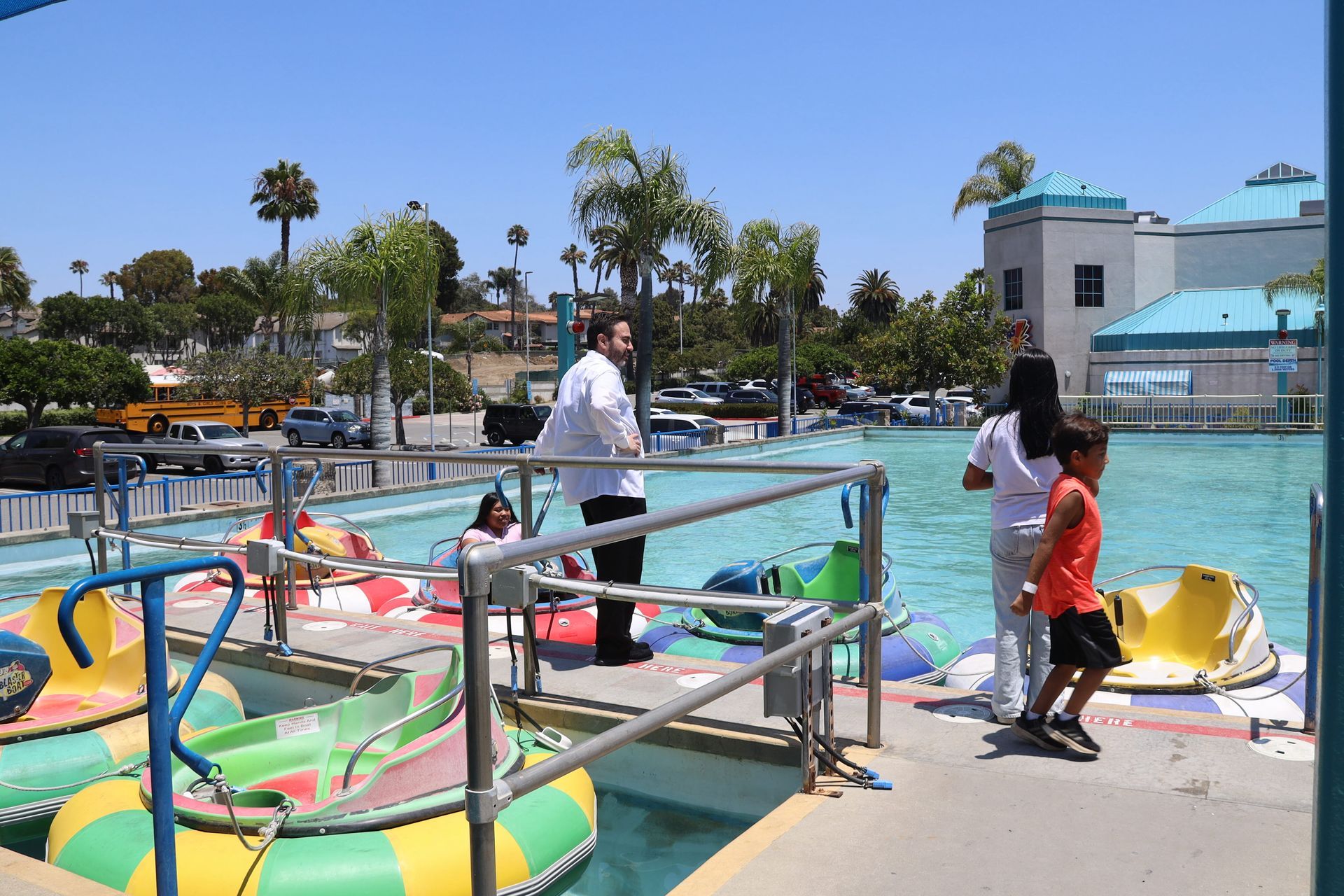People standing by colorful inflatable boats at a sunny water park dock