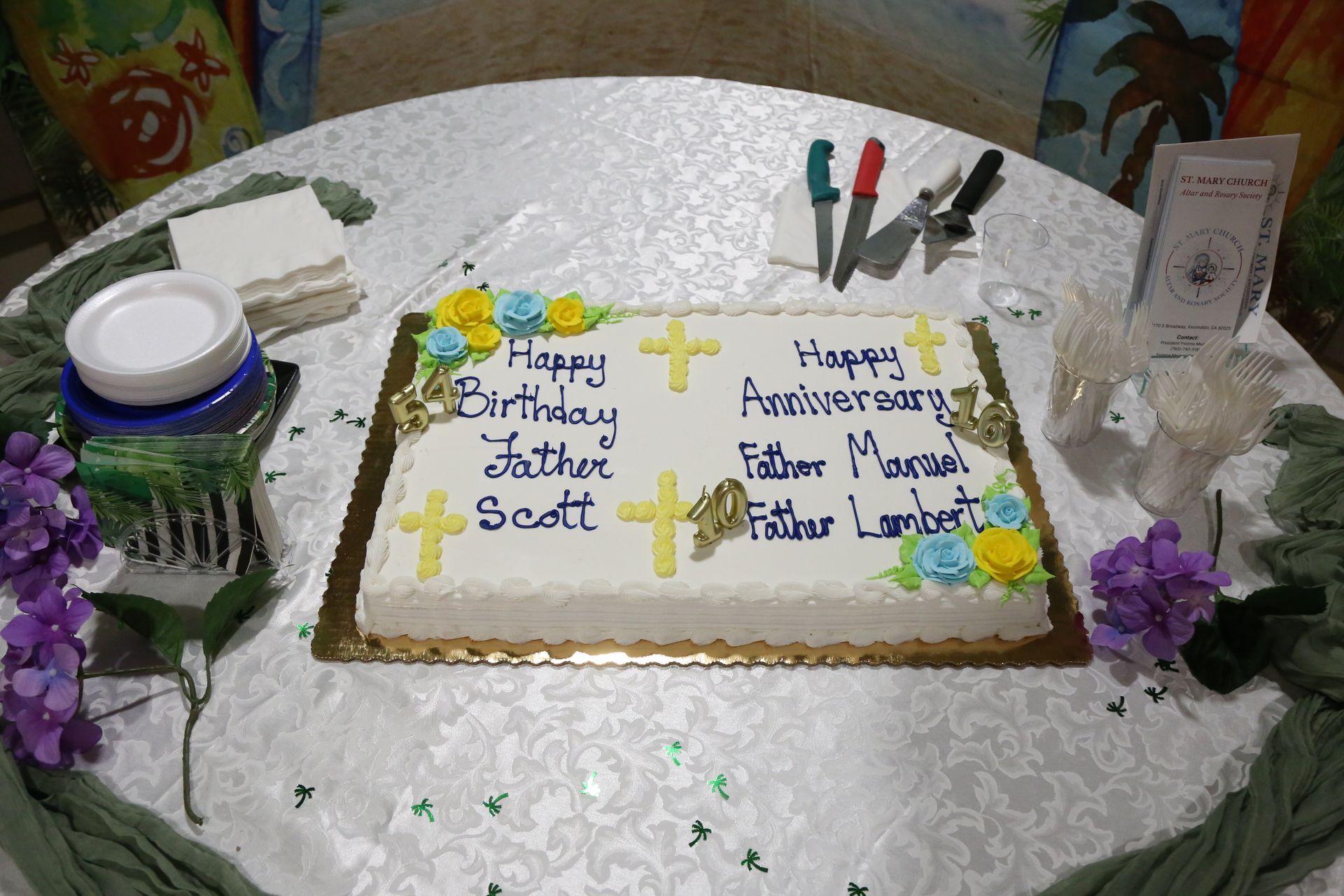 Decorated birthday cake with white icing, yellow flowers, and purple accents on a lace-covered table