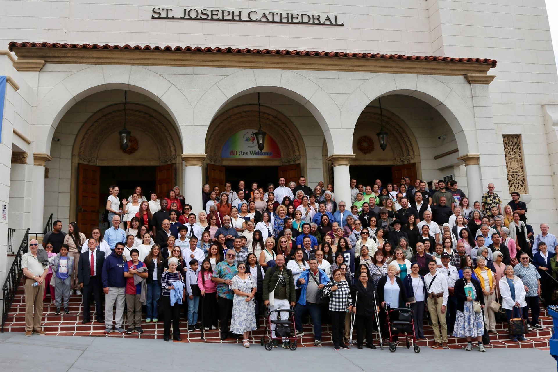 Large group posing on church steps under the St. Joseph Cathedral arches