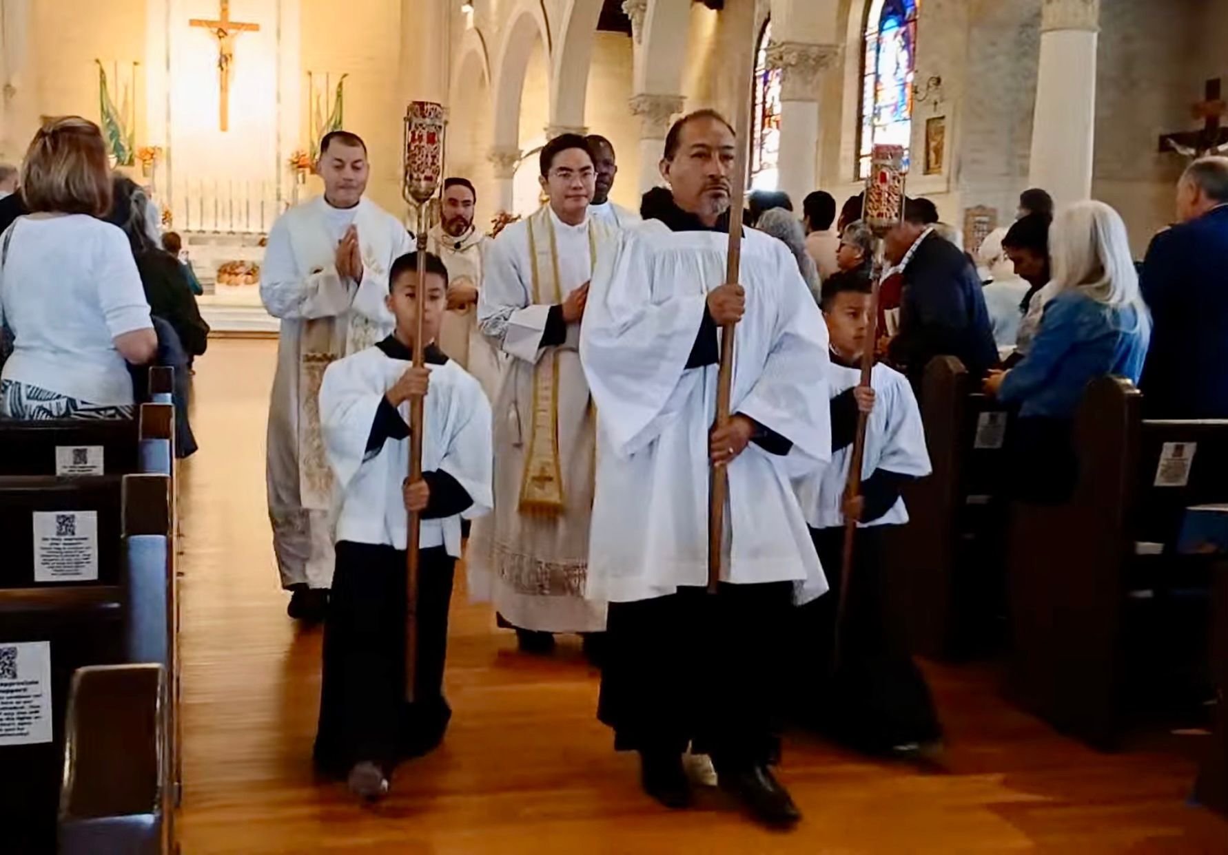Clergy and altar servers processing down the aisle in a church during a service