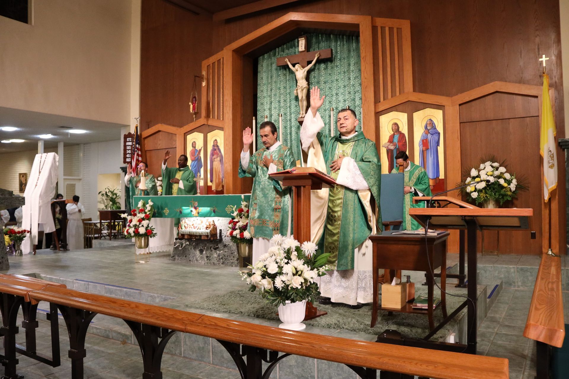 Priest at church altar during Mass, with crucifix and green vestments behind him