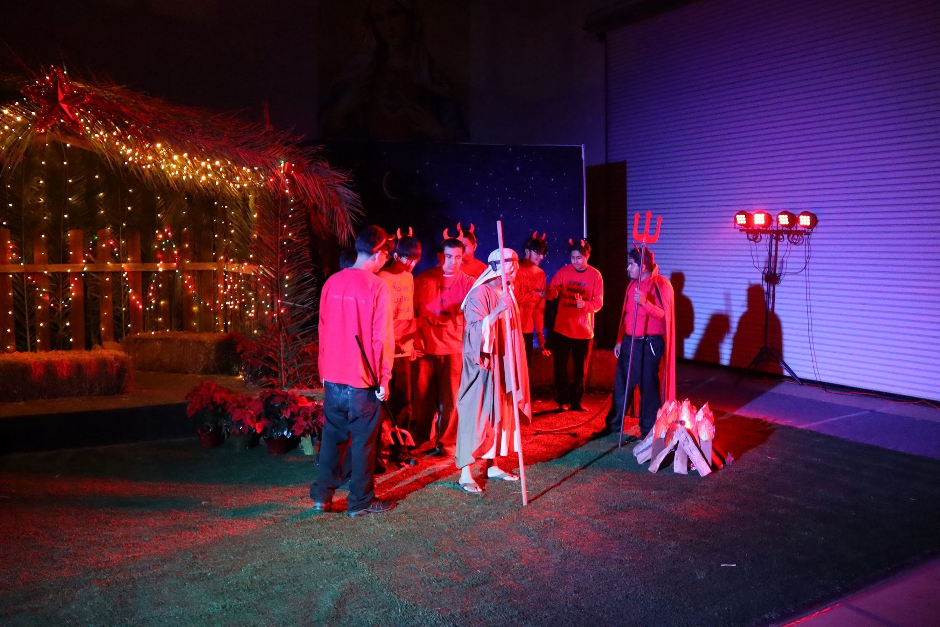 People setting up tripods and lights in a dark outdoor area with red and purple lighting