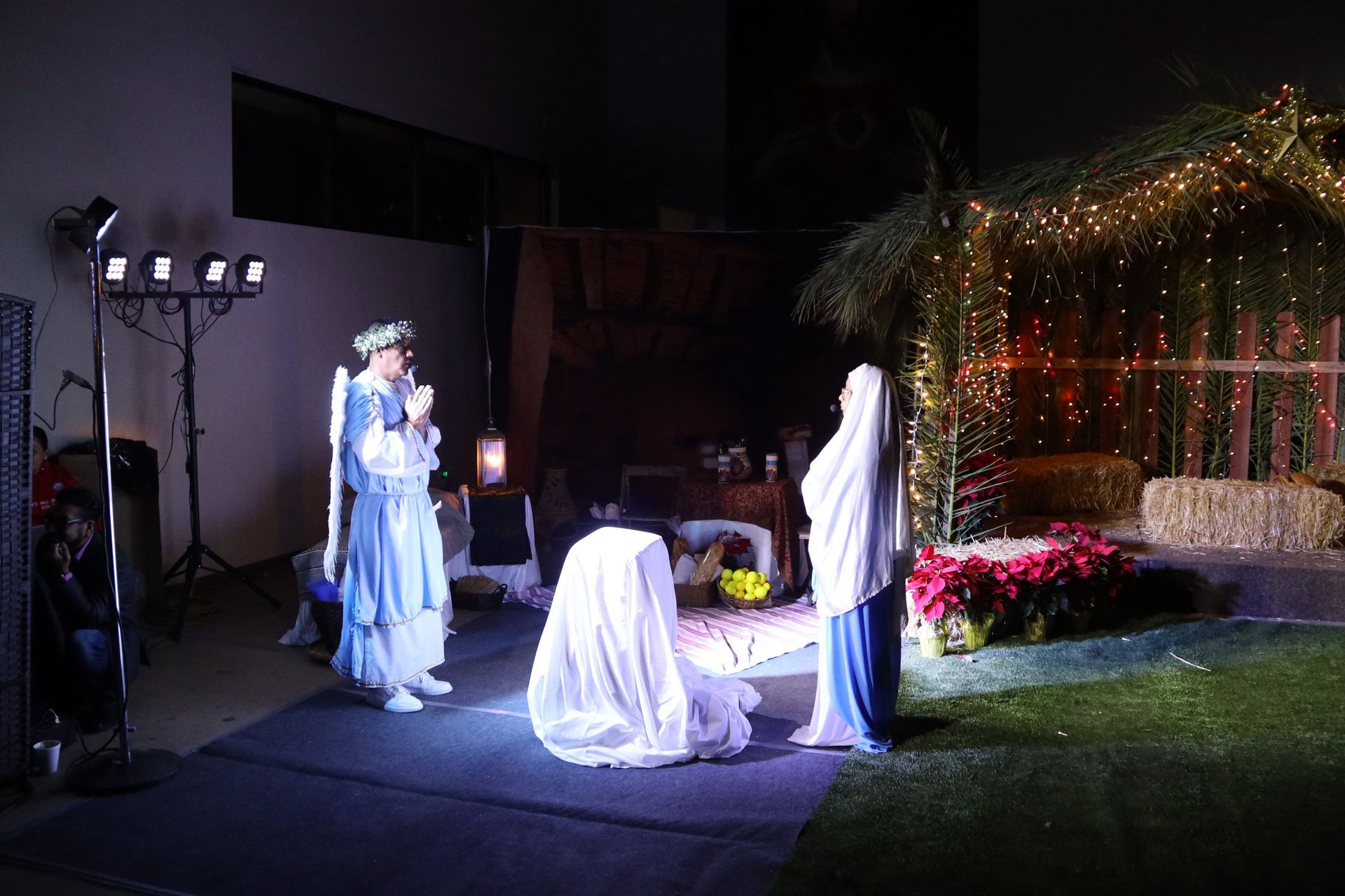 Outdoor nativity scene with three actors in robes under stage lights at night