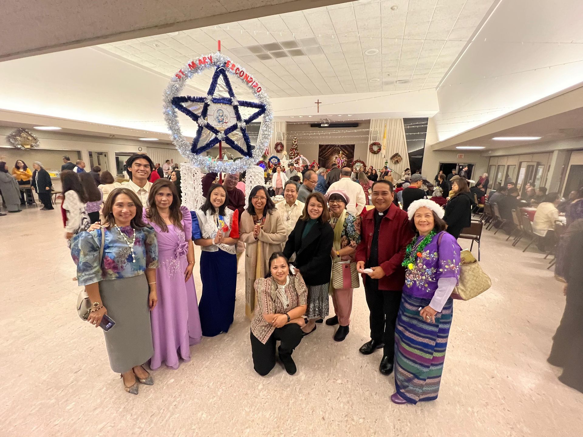 Group of people posing in a bright lobby beneath a large star-shaped hanging decoration