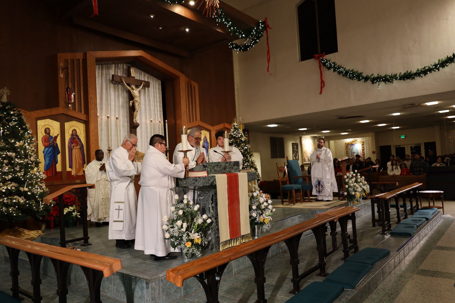Church service with priests in white robes at a decorated altar during a holiday mass