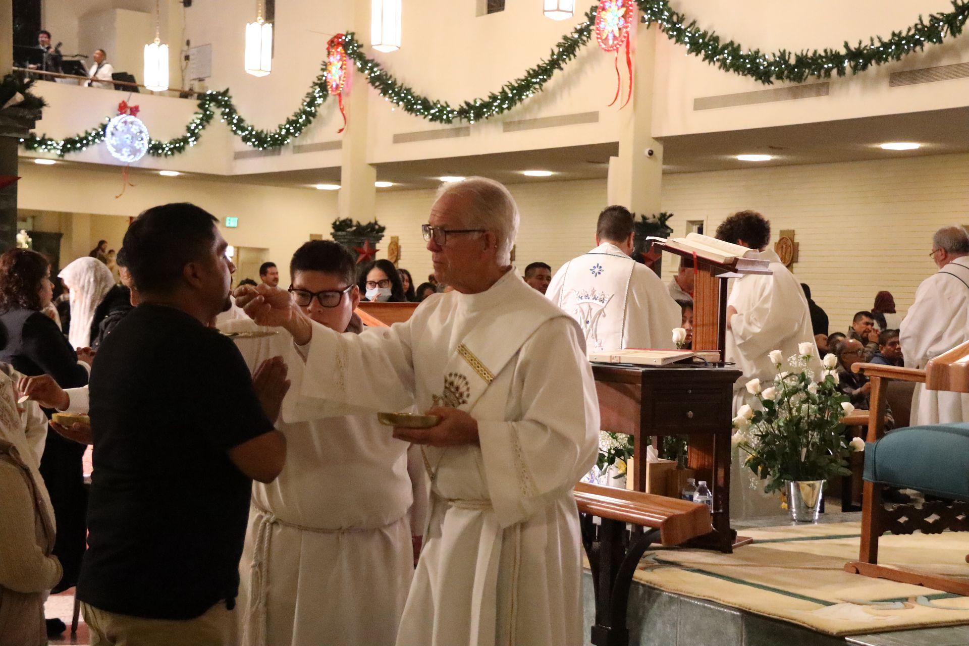 Priest in white vestments talking with a man in a church during a festive service
