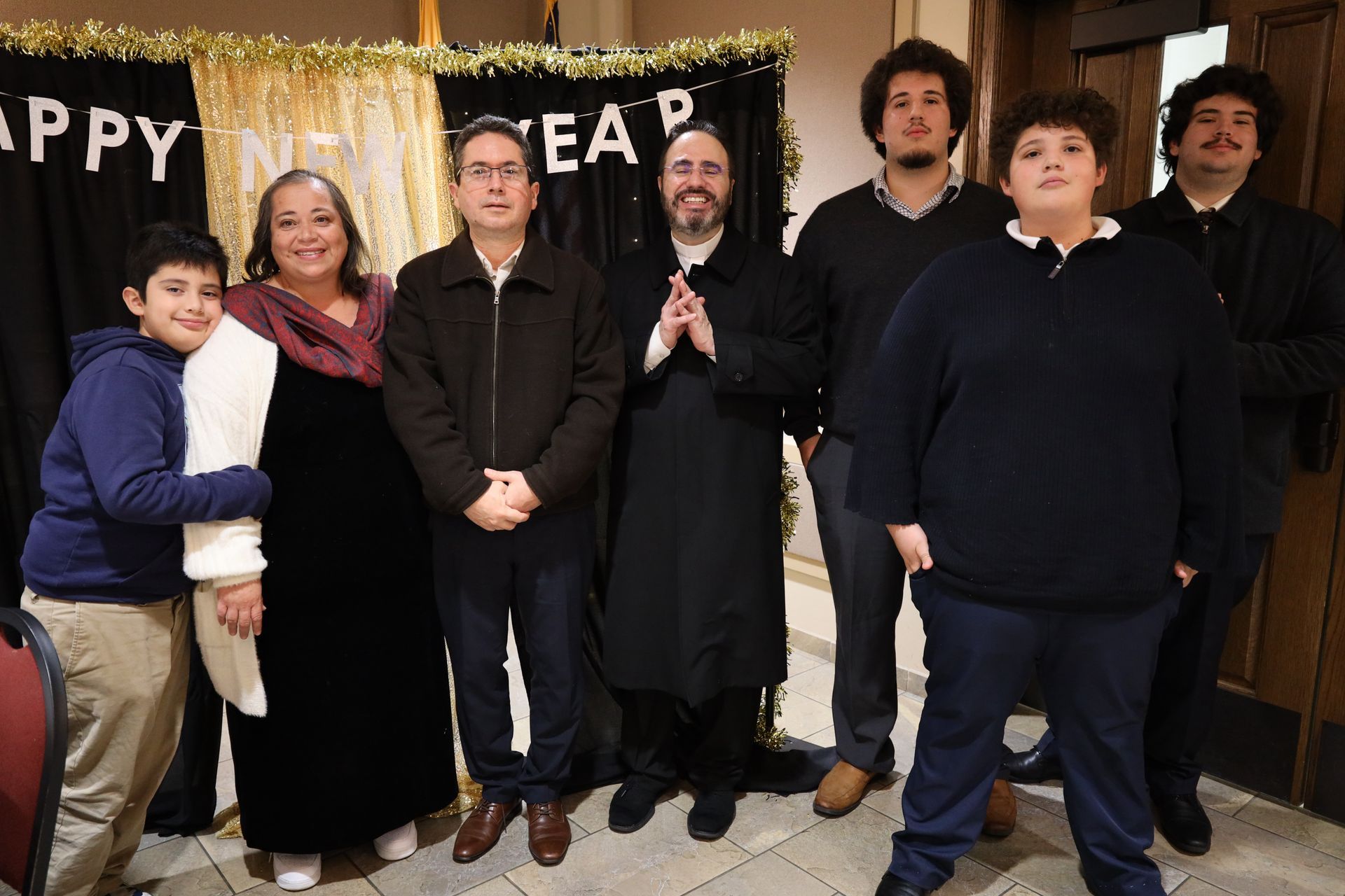 Group of people standing together indoors in front of a “Happy New Year” banner.
