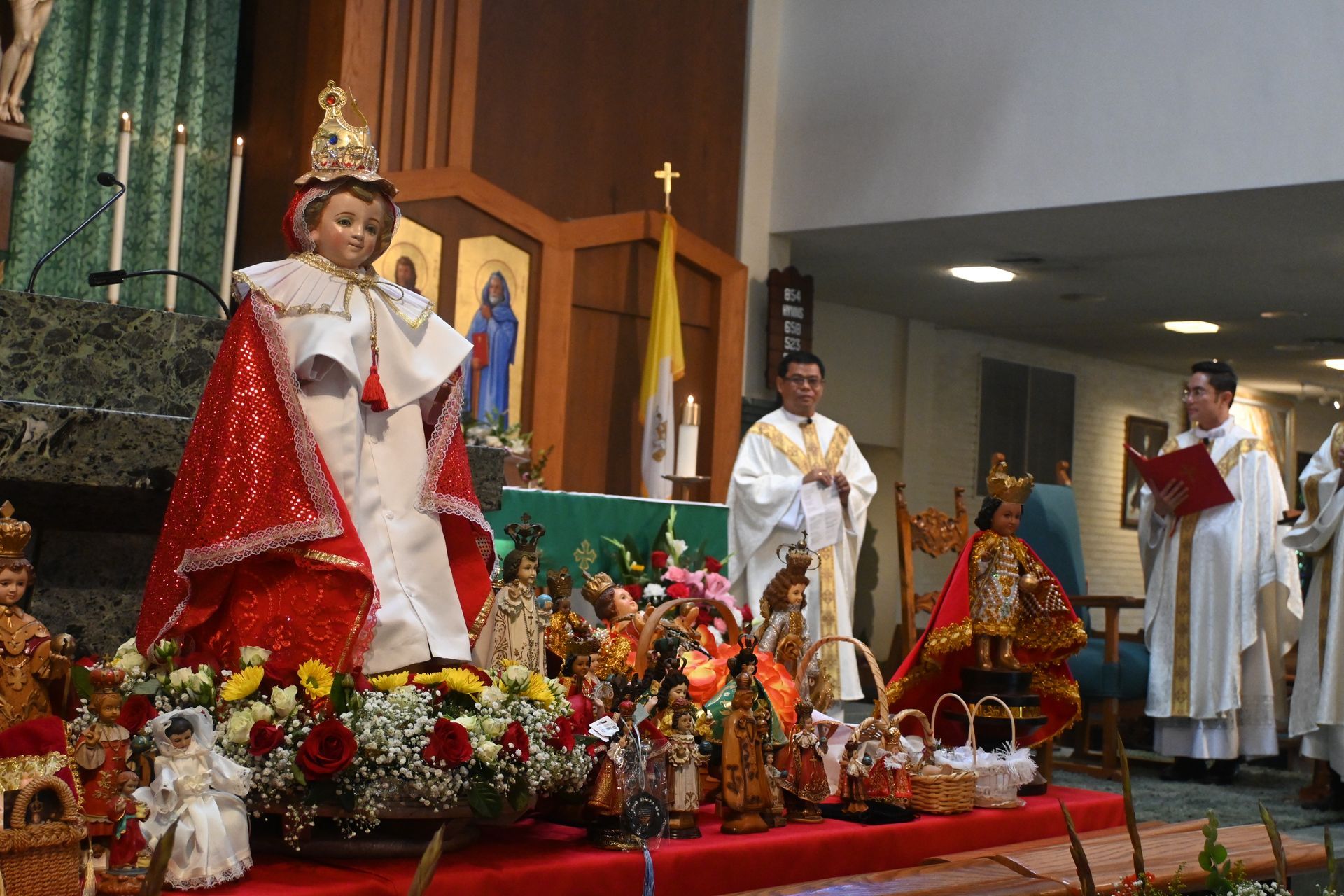 Religious ceremony with statues and clergy on a decorated altar inside a church