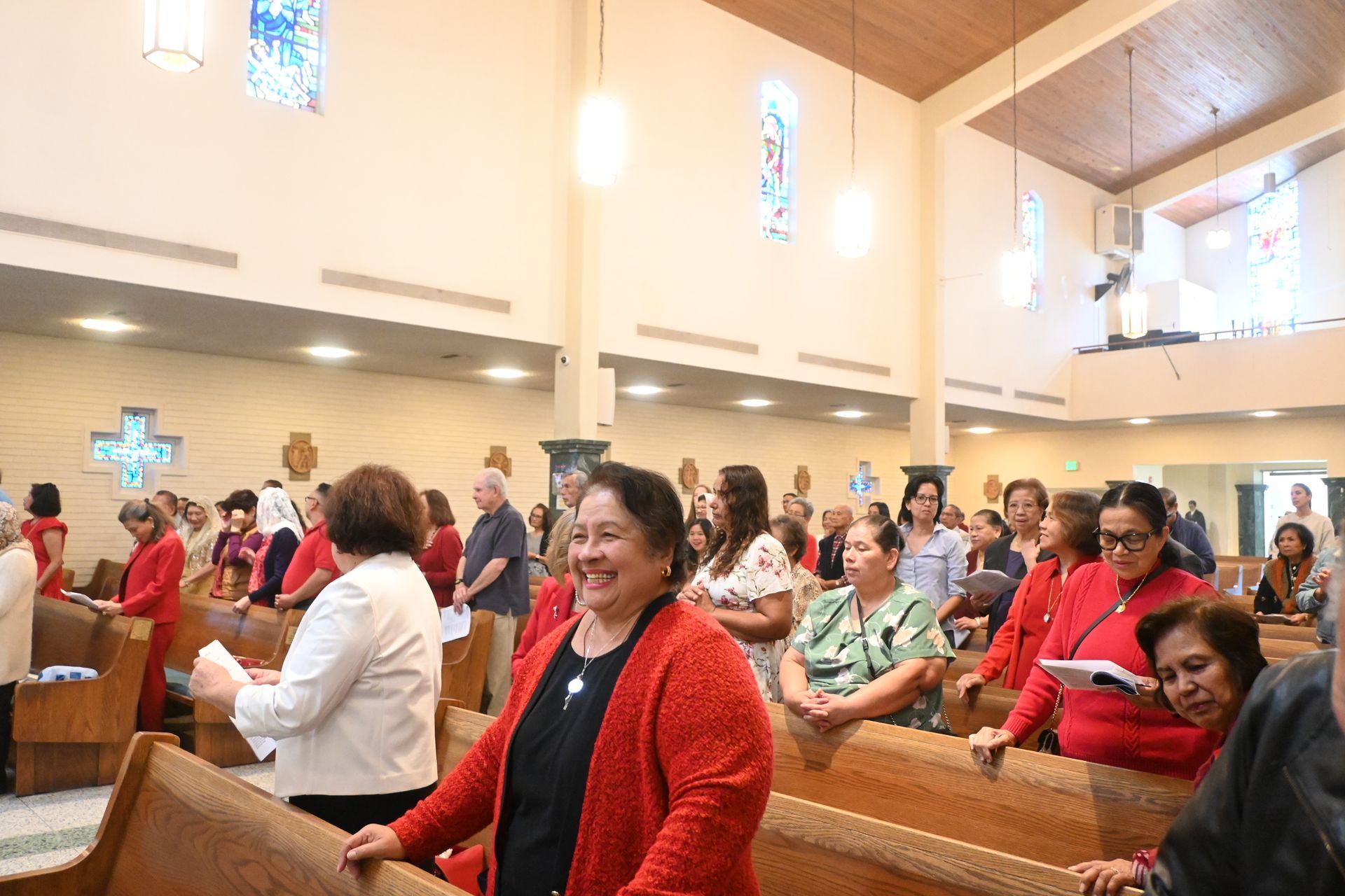 Congregants seated in a bright church, smiling and singing during a service